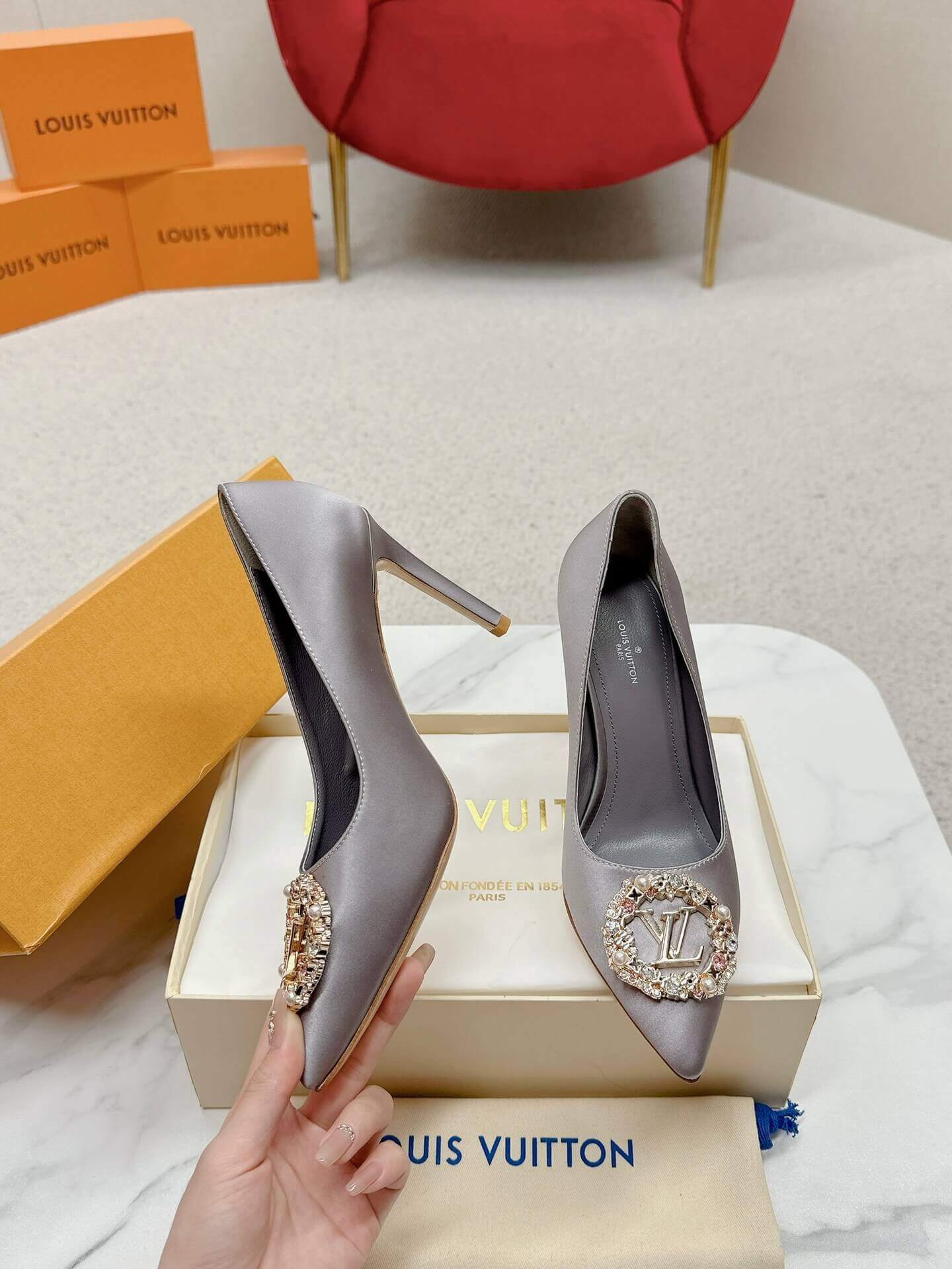 a pair of Louis Vuitton Elegant Crystal Pointed-Toe Pump – Grey on a marble table