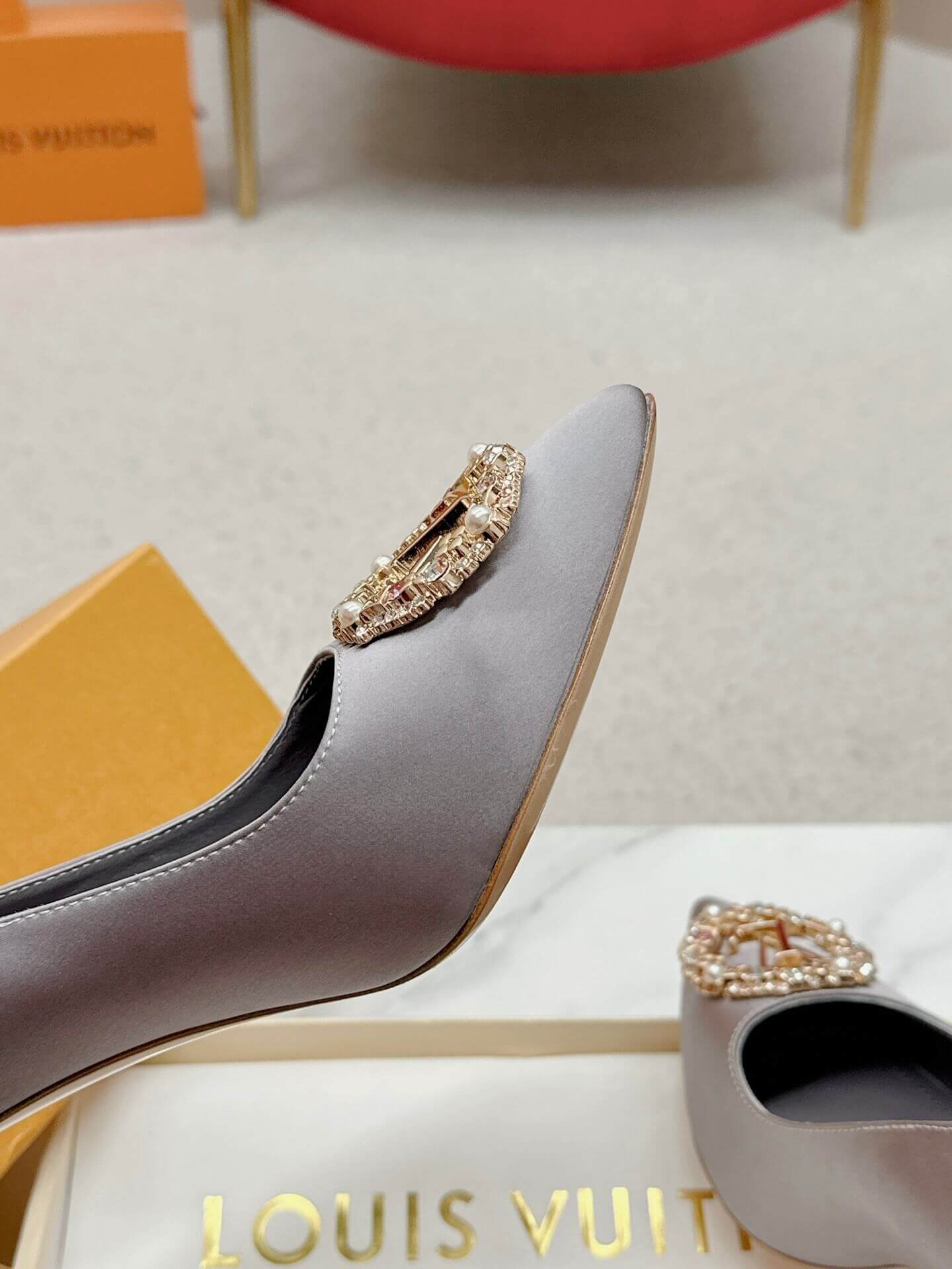 a pair of Louis Vuitton Elegant Crystal Pointed-Toe Pump – Grey on a marble table