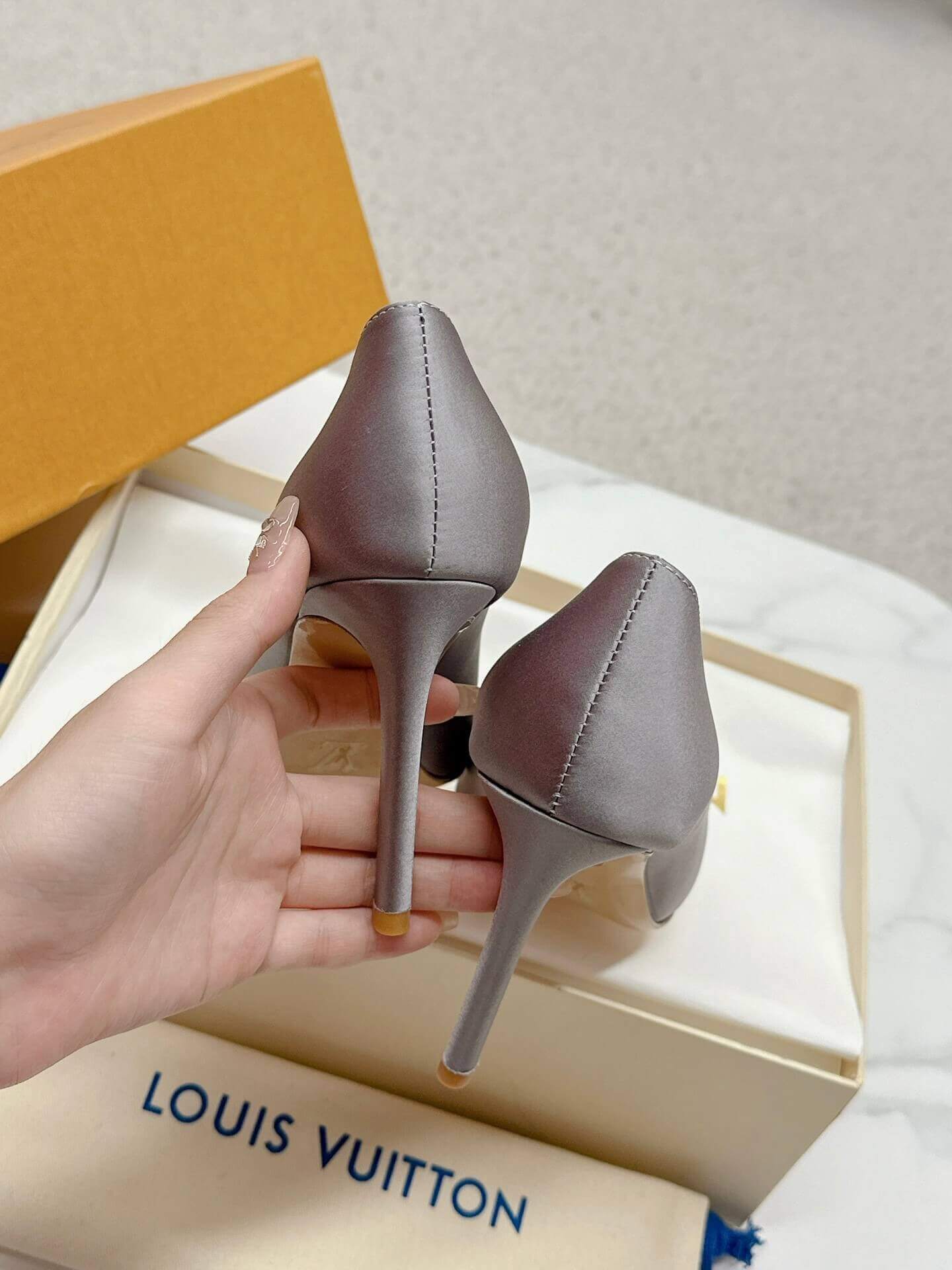 a pair of Louis Vuitton Elegant Crystal Pointed-Toe Pump – Grey on a marble table