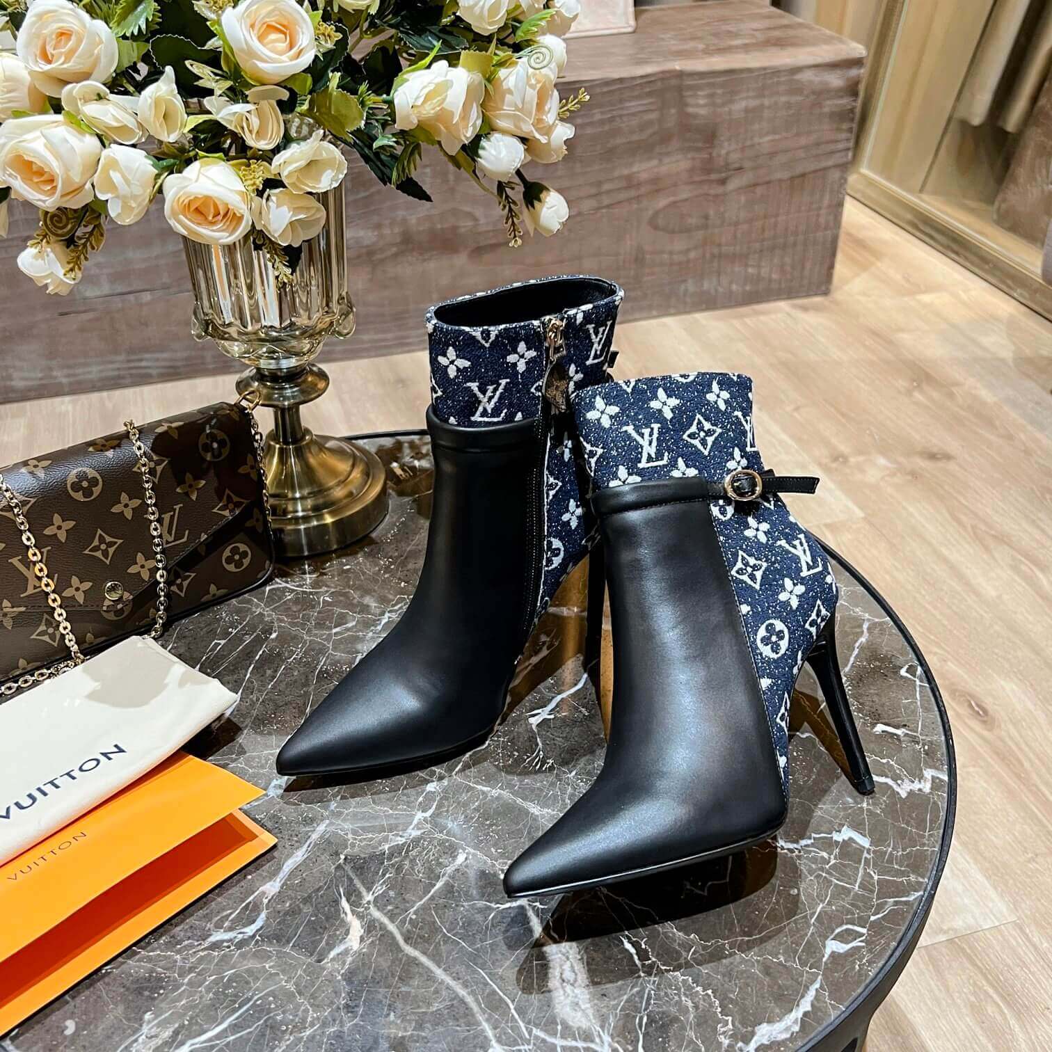 a pair of Louis Vuitton High-Heeled Ankle Boots In Black & Blue Monogram on a marble table