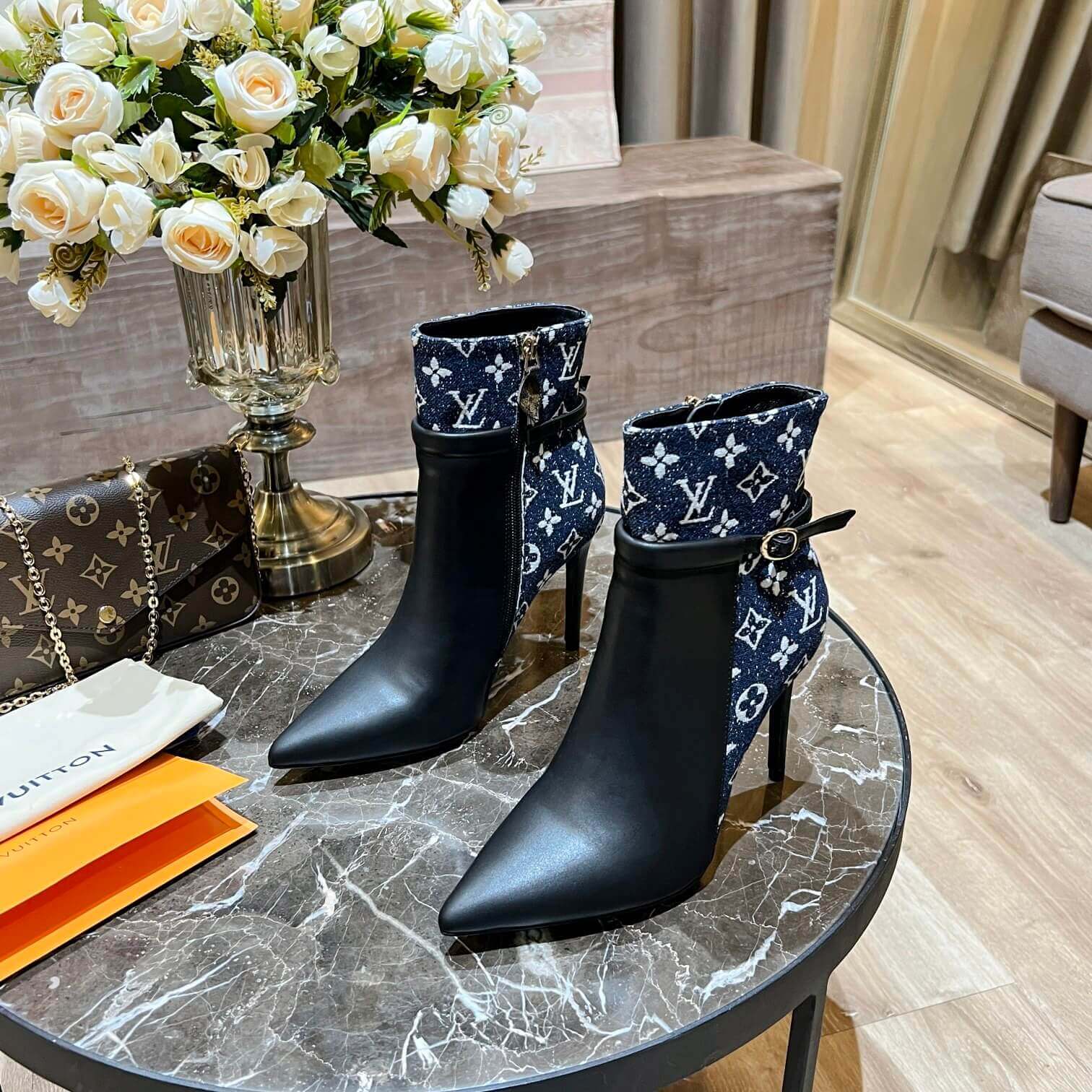 a pair of Louis Vuitton High-Heeled Ankle Boots In Black & Blue Monogram on a marble table