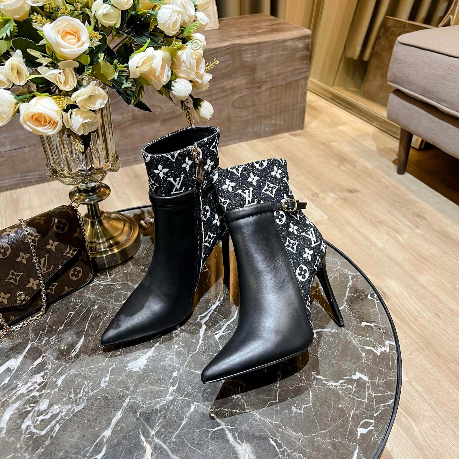 a pair of Louis Vuitton High-Heeled Ankle Boots In Black & Blue Monogram on a marble table