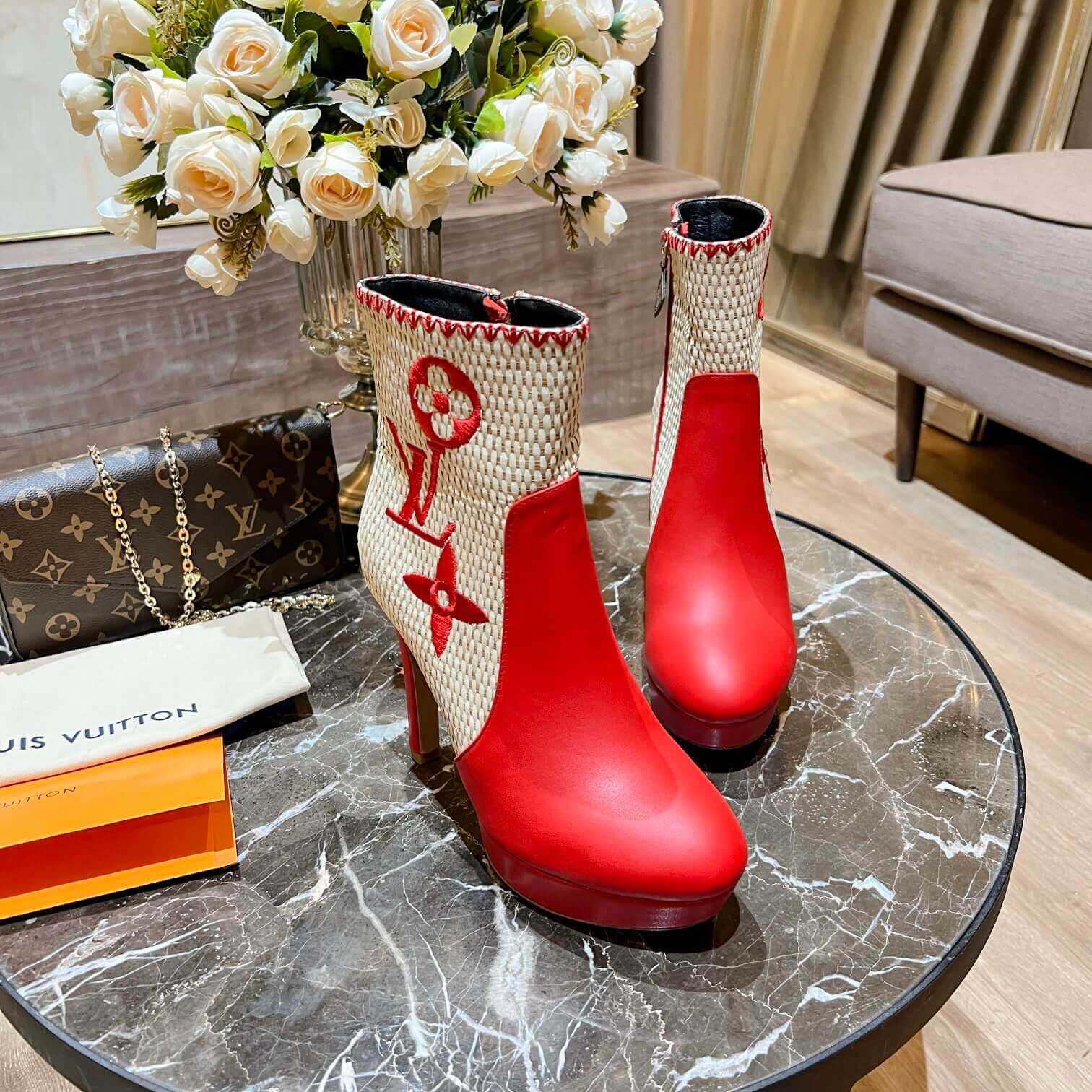 a pair of Louis Vuitton High-Heeled Ankle Boots In Red & Embroidered Monogramon a marble table