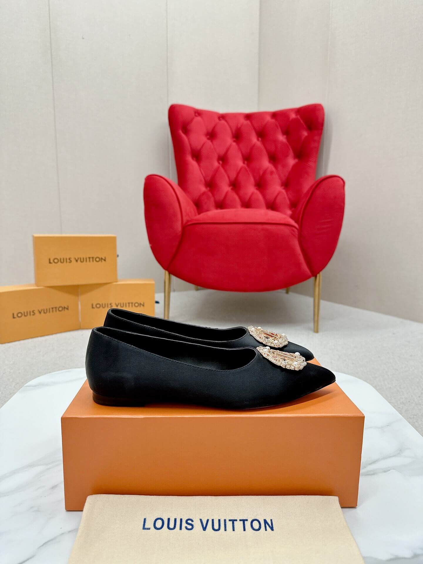 a pair of Louis Vuitton Inspired Crystal Embellished Satin Flats in Black on a marble table chair