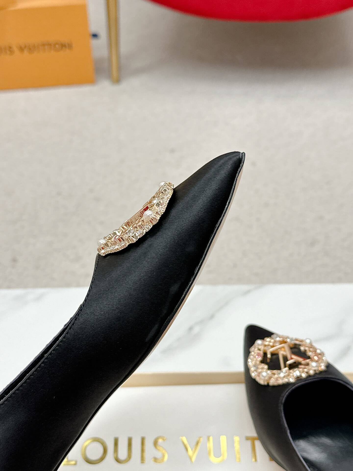 a pair of Louis Vuitton Inspired Crystal Embellished Satin Flats in Black on a marble table chair