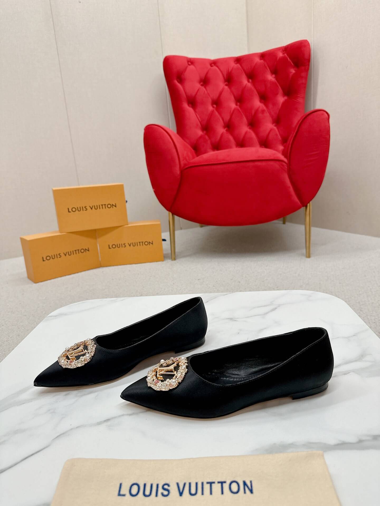 a pair of Louis Vuitton Inspired Crystal Embellished Satin Flats in Black on a marble table chair