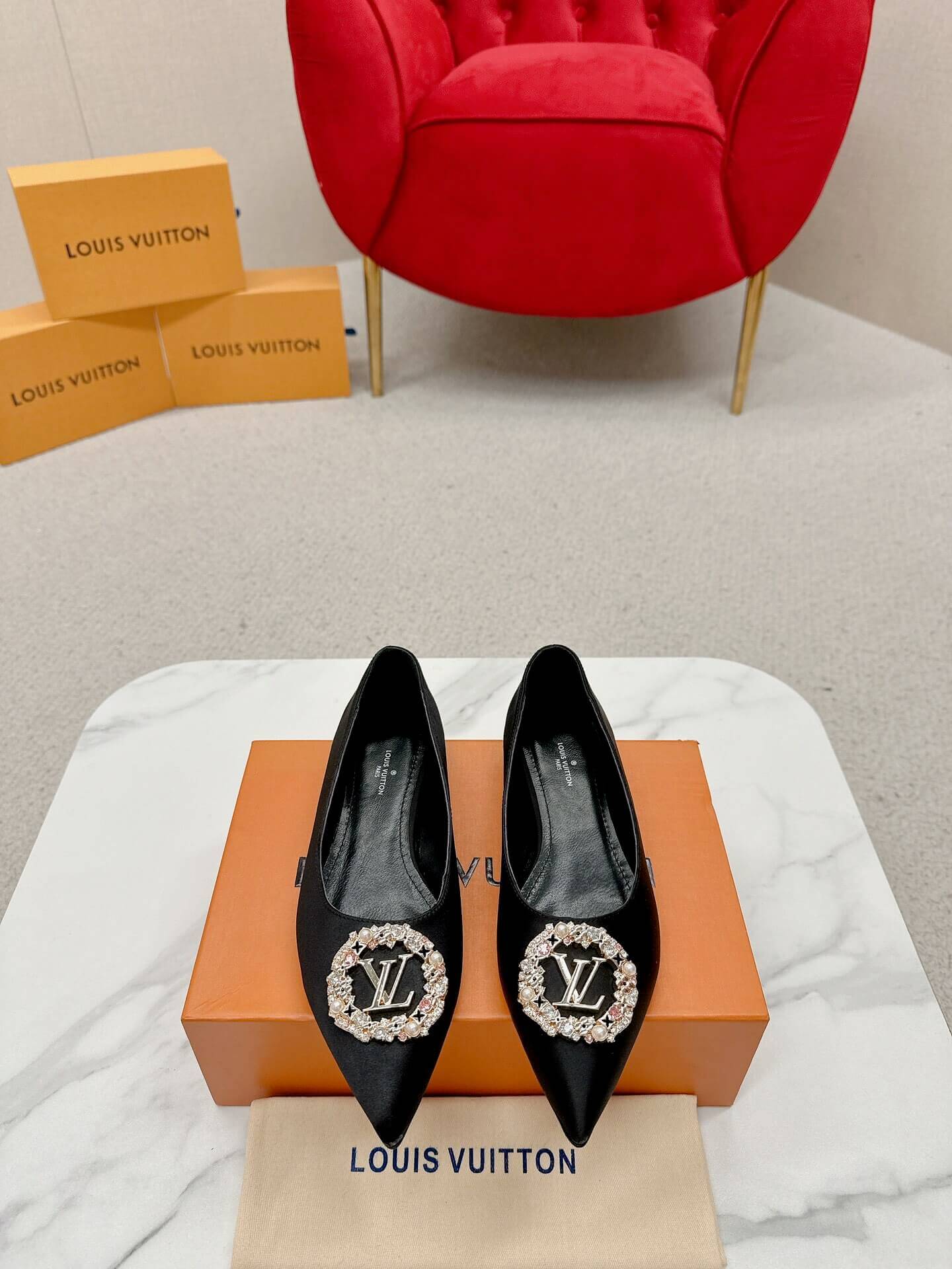 a pair of Louis Vuitton Inspired Crystal Embellished Satin Flats in Black on a marble table chair
