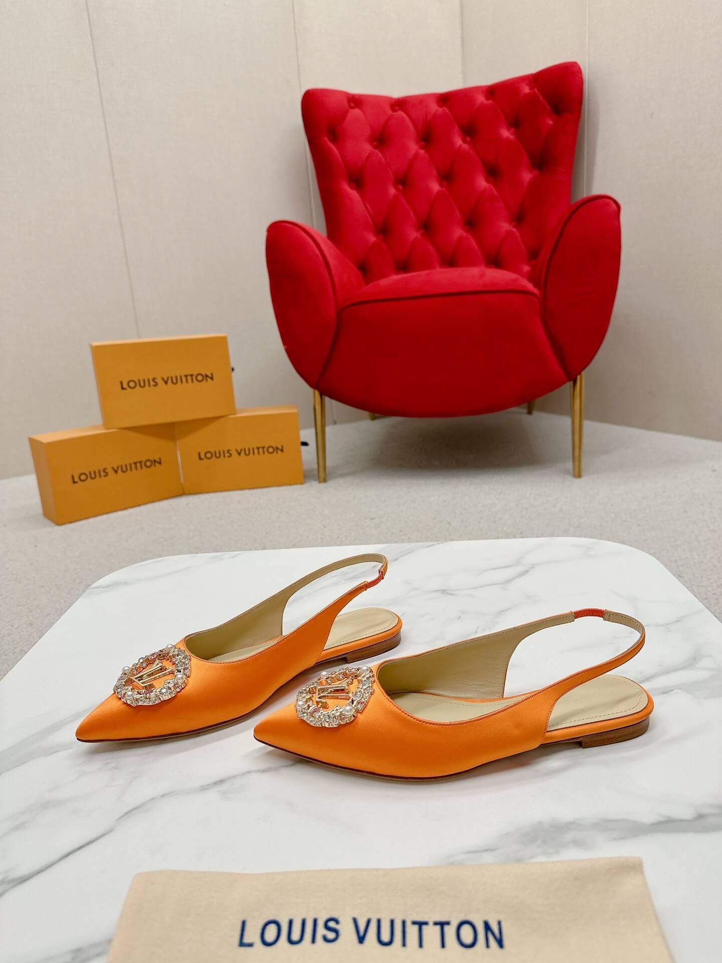 a pair of Louis Vuitton Inspired Crystal Slingback – Orange Luxe Edition on a marble table
