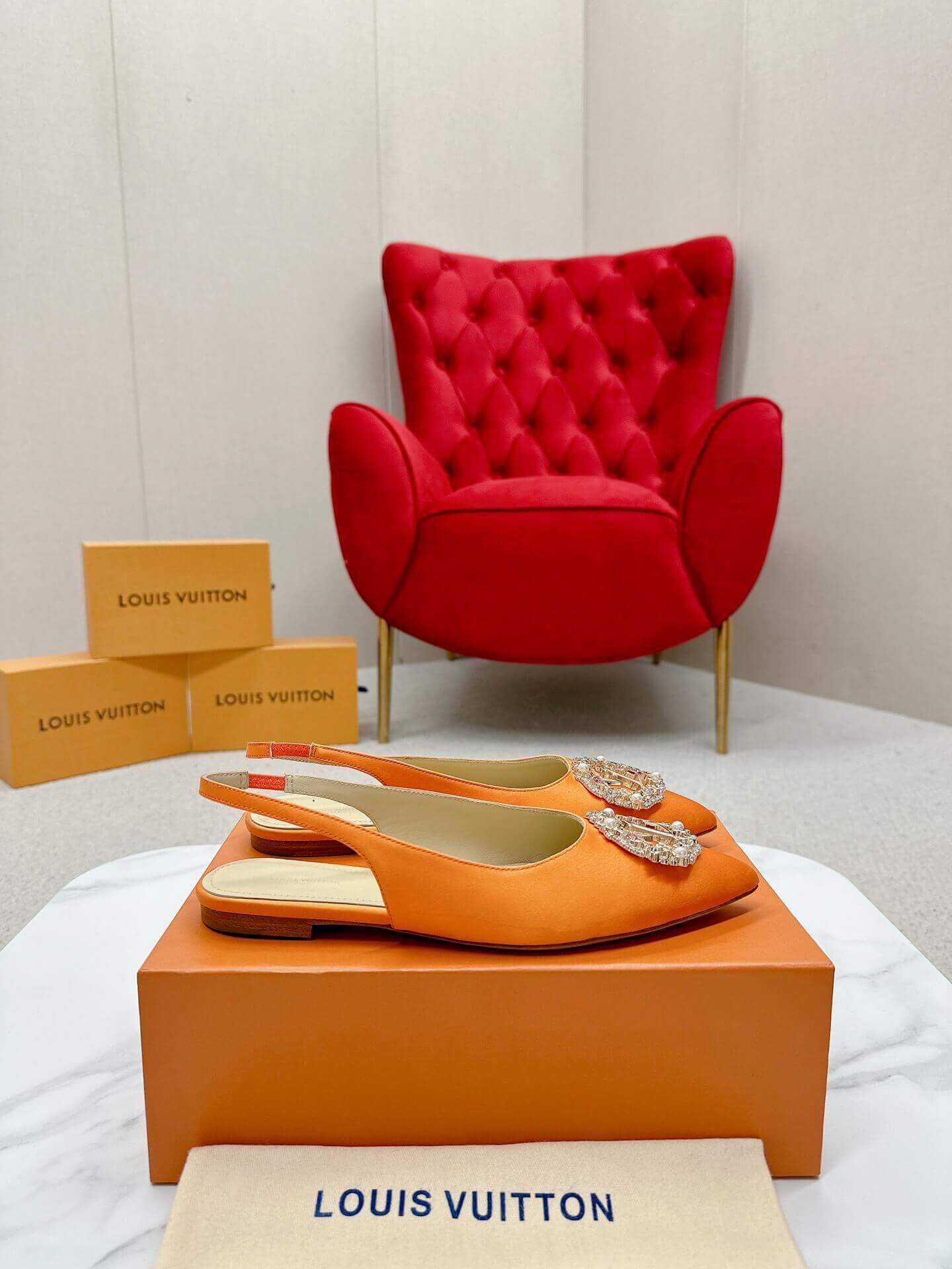 a pair of Louis Vuitton Inspired Crystal Slingback – Orange Luxe Edition on a marble table
