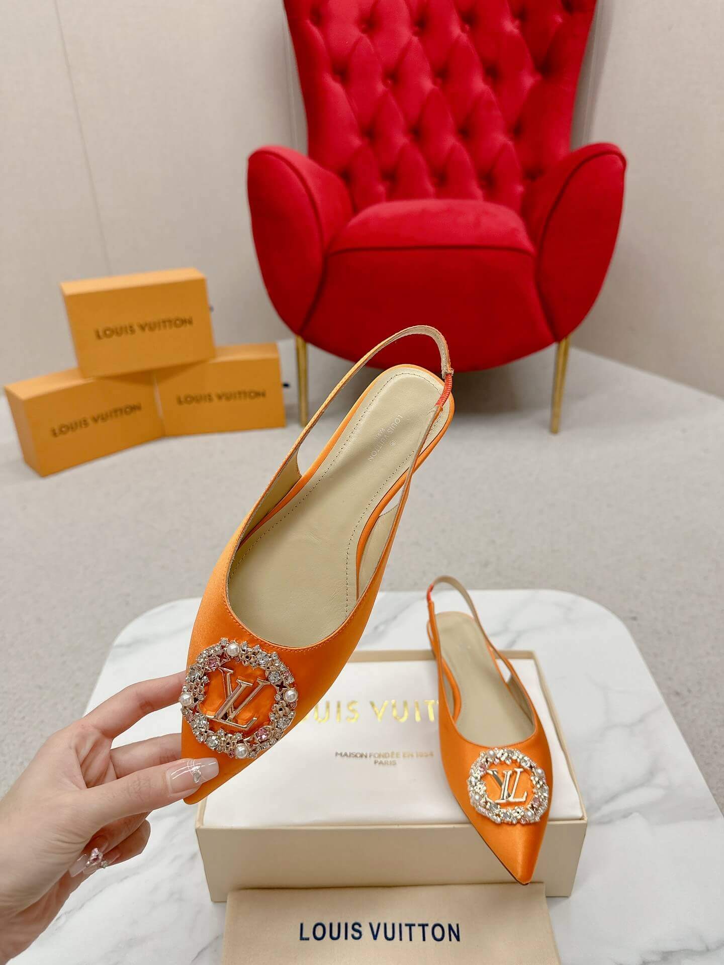 a pair of Louis Vuitton Inspired Crystal Slingback – Orange Luxe Edition on a marble table