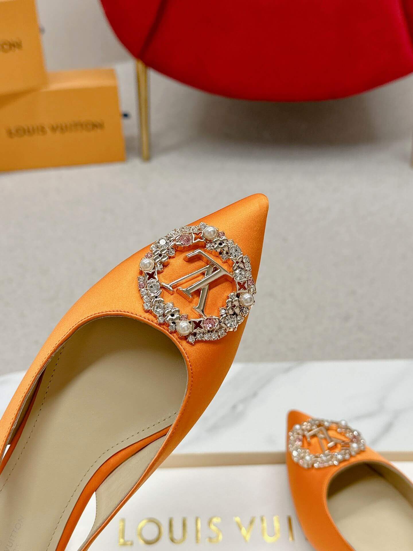 a pair of Louis Vuitton Inspired Crystal Slingback – Orange Luxe Edition on a marble table