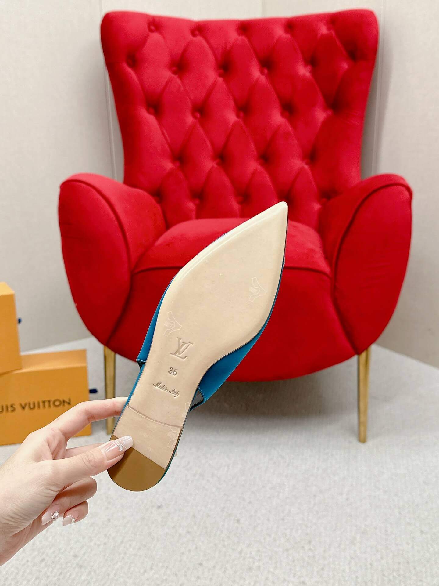 a pair ofLouis Vuitton Madeleine Crystal Slingback –In Teal Blue on a marble table