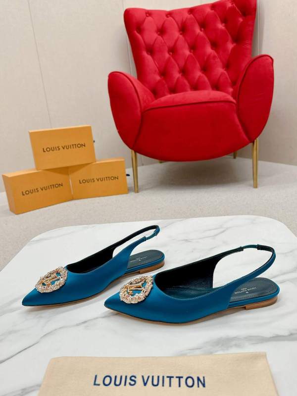 a pair ofLouis Vuitton Madeleine Crystal Slingback –In Teal Blue on a marble table