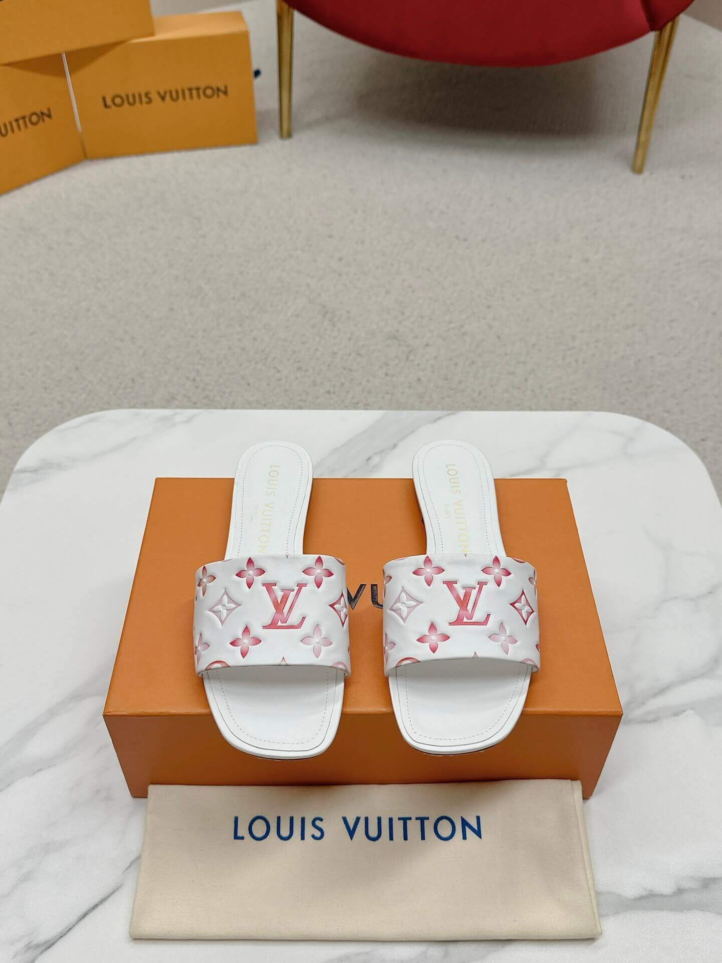 a pair of Louis Vuitton White Monogram Slide Sandals – Pink Edition on a marble surface
