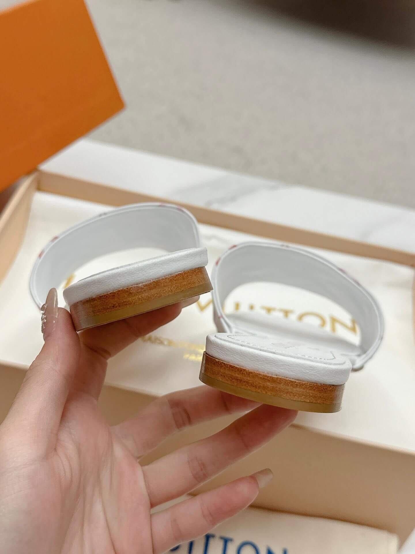 a pair of Louis Vuitton White Monogram Slide Sandals – Pink Edition on a marble surface