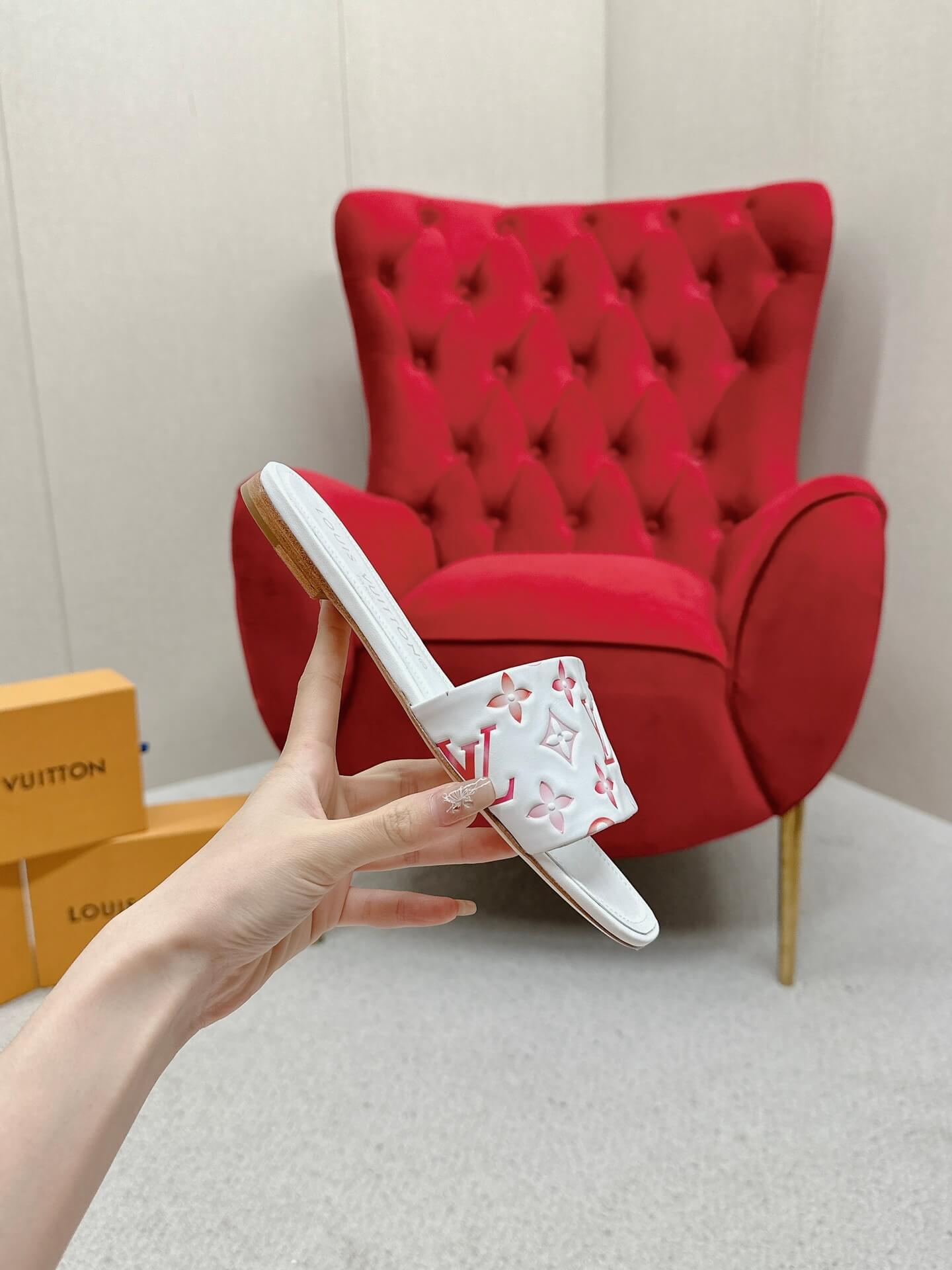 a pair of Louis Vuitton White Monogram Slide Sandals – Pink Edition on a marble surface