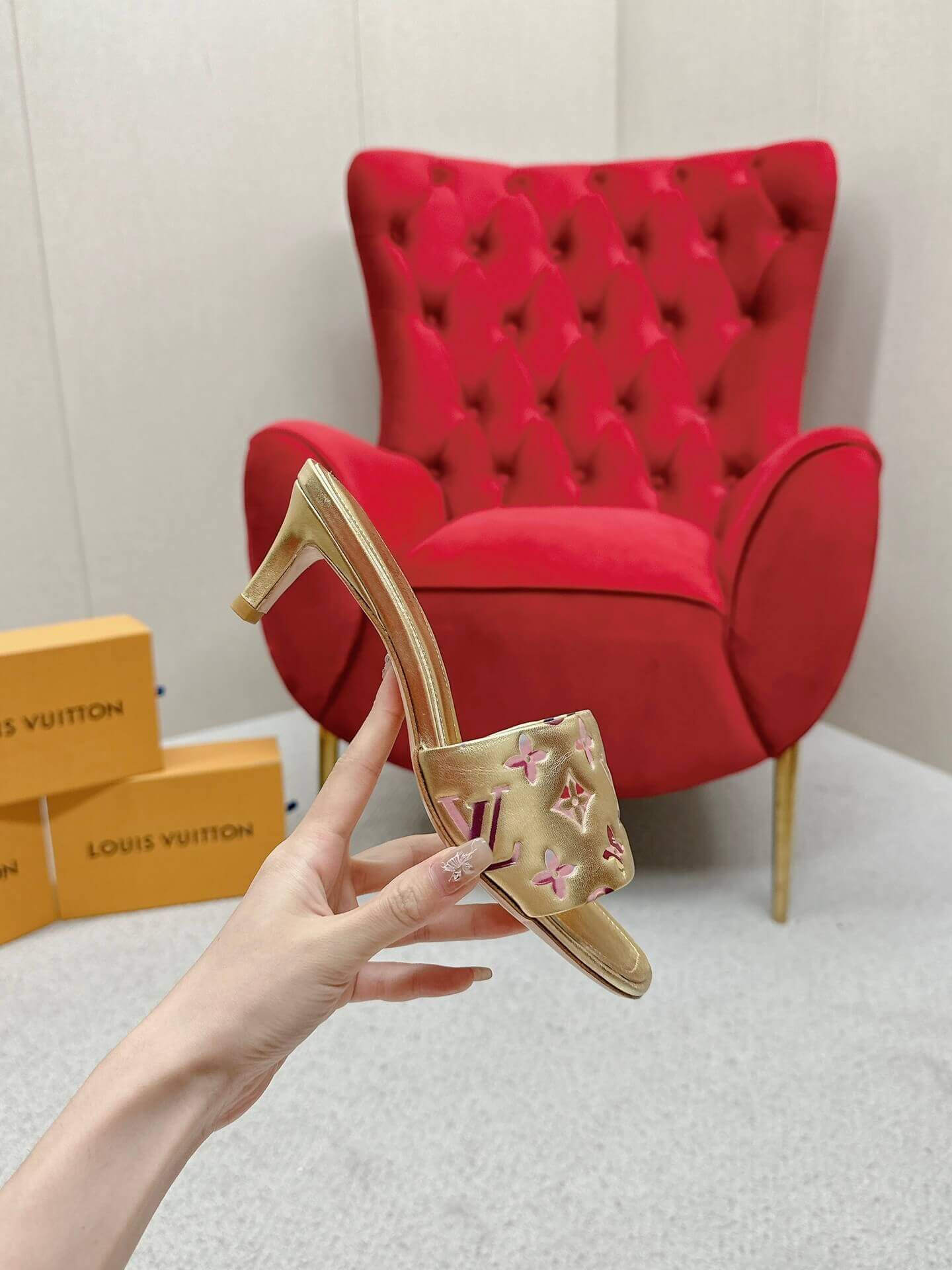 a pair of Louis Vuitton Revival Mule in Gold Monogram-Embossed Lambskin Heel on a marble surface