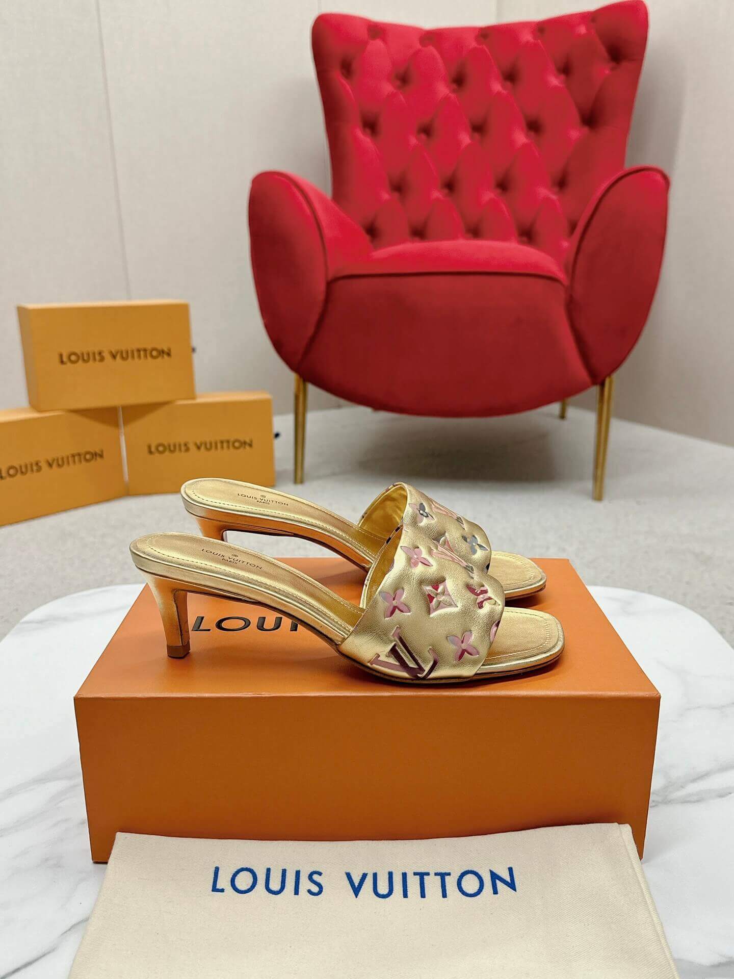 a pair of Louis Vuitton Revival Mule in Gold Monogram-Embossed Lambskin Heel on a marble surface