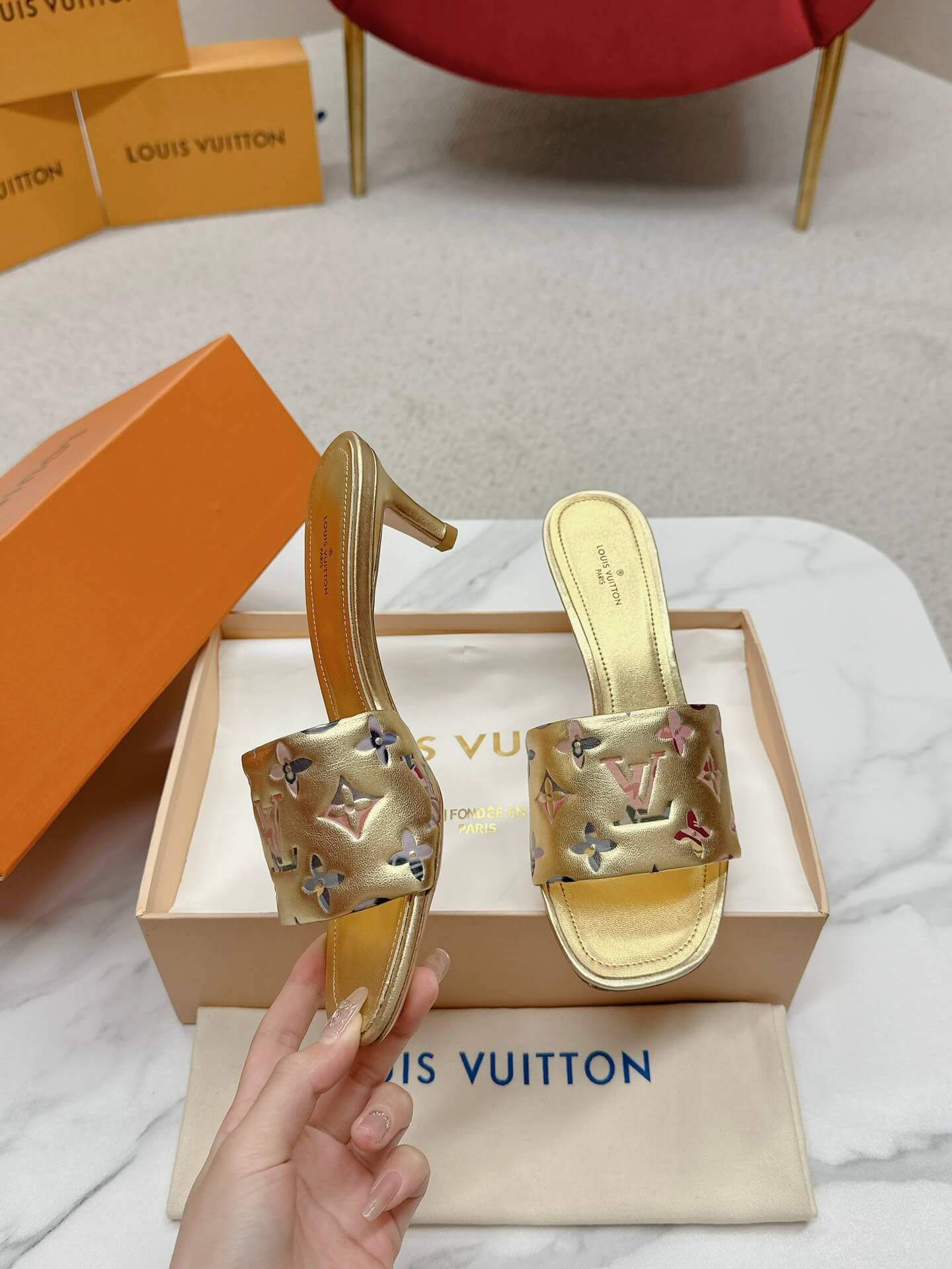 a pair of Louis Vuitton Revival Mule in Gold Monogram-Embossed Lambskin Heel on a marble surface