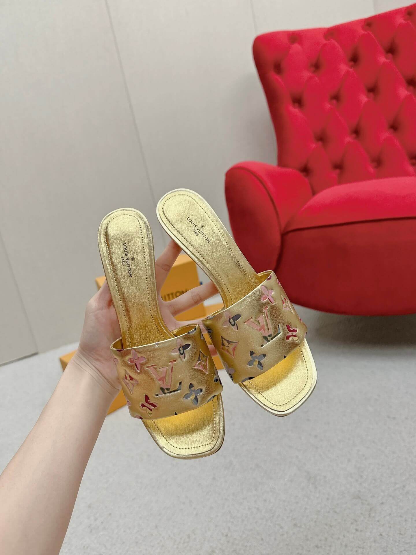 a pair of Louis Vuitton Revival Mule in Gold Monogram-Embossed Lambskin Heel on a marble surface
