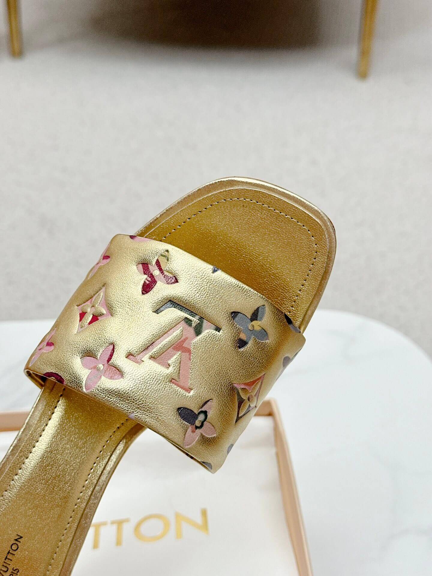 a pair of Louis Vuitton Revival Mule in Gold Monogram-Embossed Lambskin Heel on a marble surface