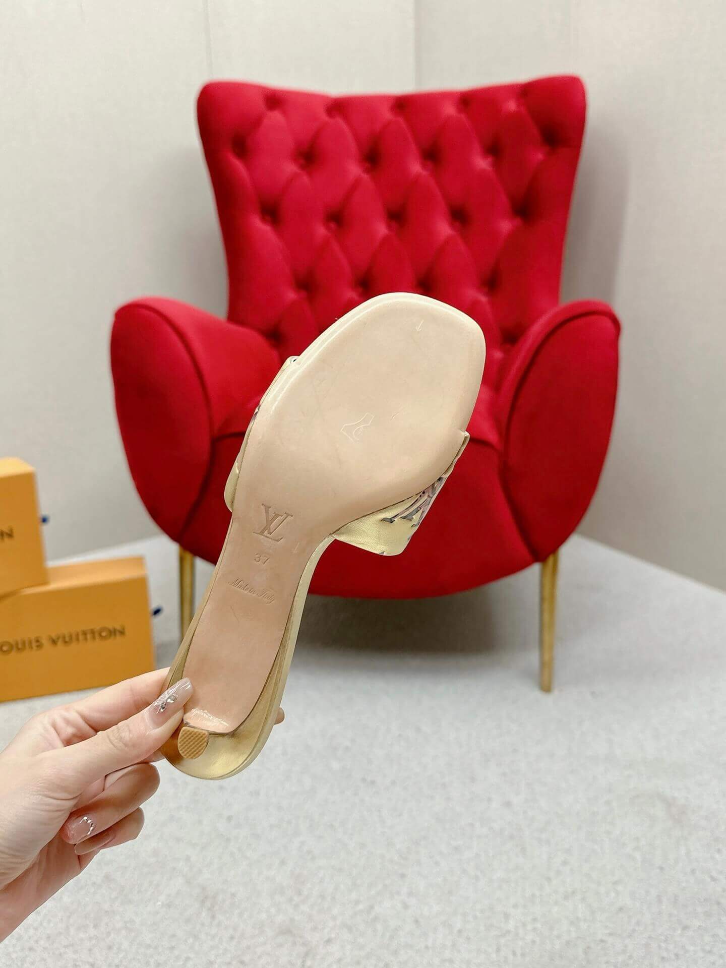 a pair of Louis Vuitton Revival Mule in Gold Monogram-Embossed Lambskin Heel on a marble surface