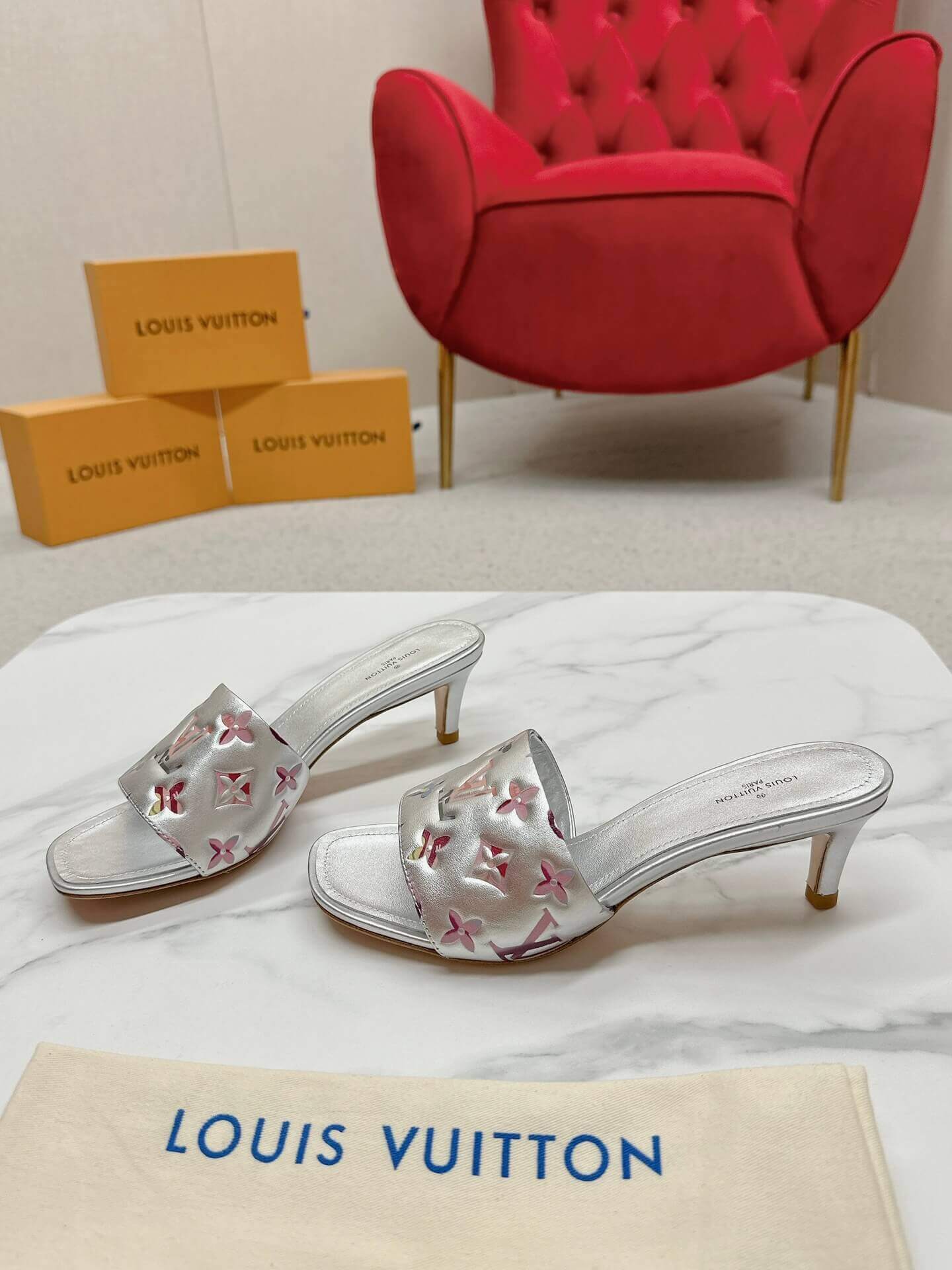 a pair of Louis Vuitton Revival Mule in Silver Metallic Monogram‑Embossed Heel on a marble surface