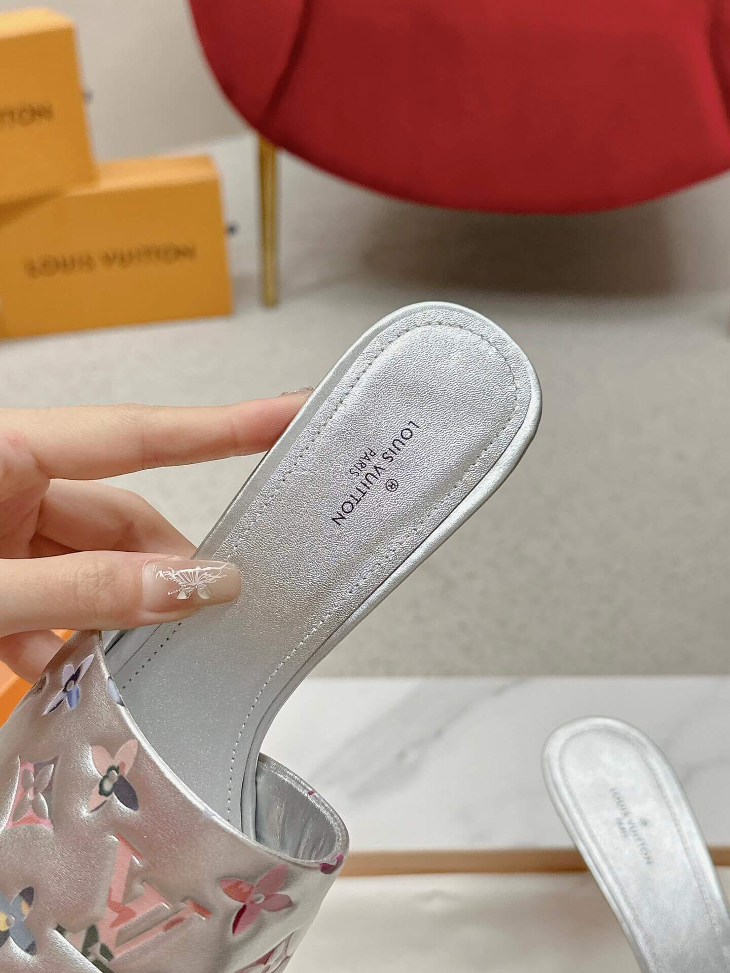 a pair of Louis Vuitton Revival Mule in Silver Metallic Monogram‑Embossed Heel on a marble surface