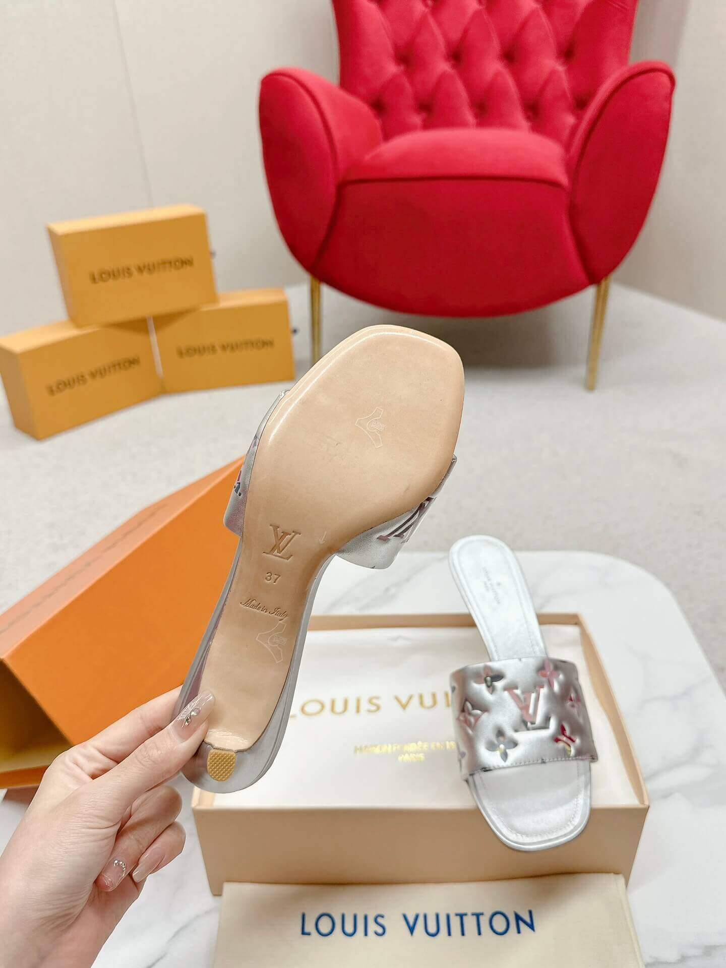 a pair of Louis Vuitton Revival Mule in Silver Metallic Monogram‑Embossed Heel on a marble surface