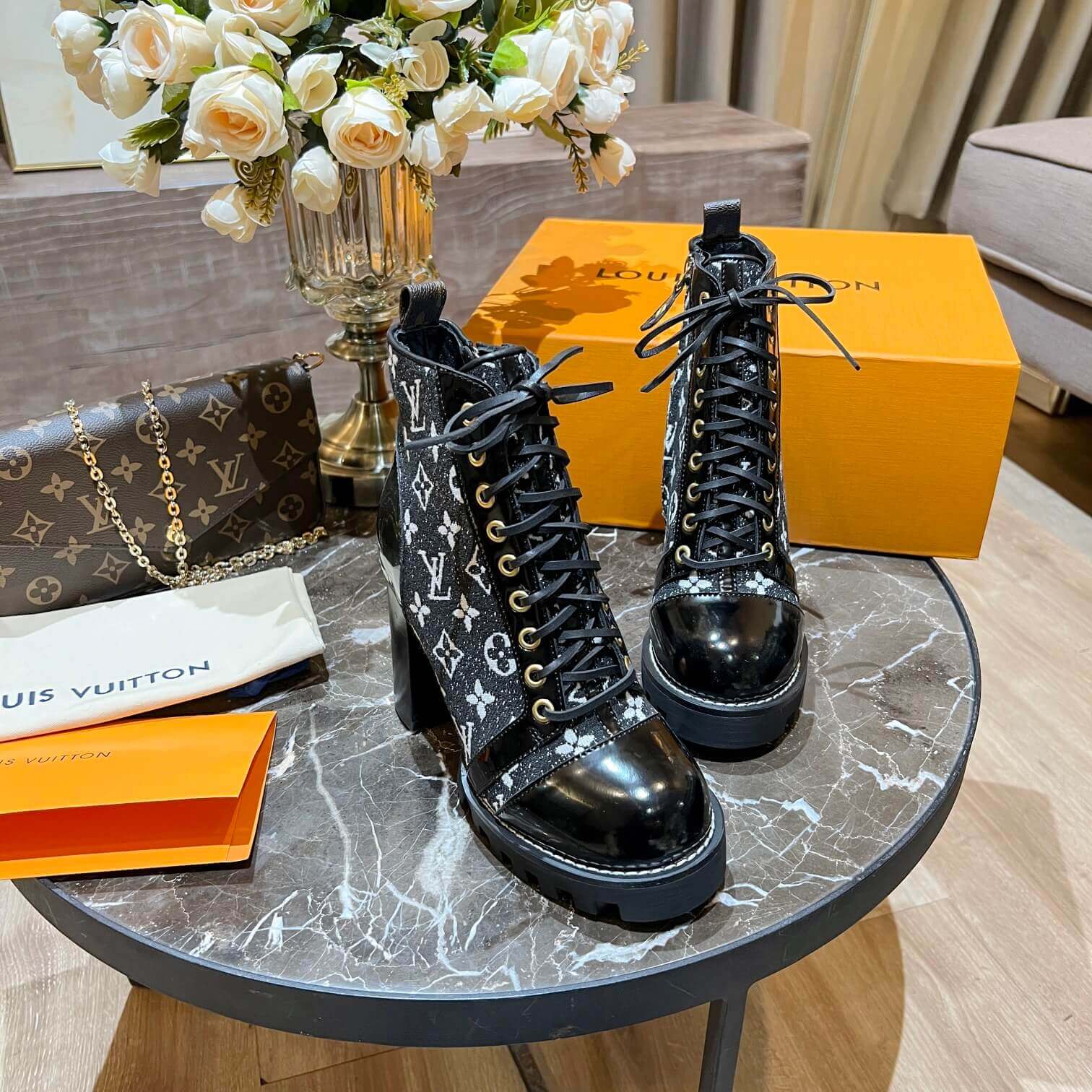 a pair of Louis Vuitton Star Trail Ankle Boots (Black Monogramon a marble table