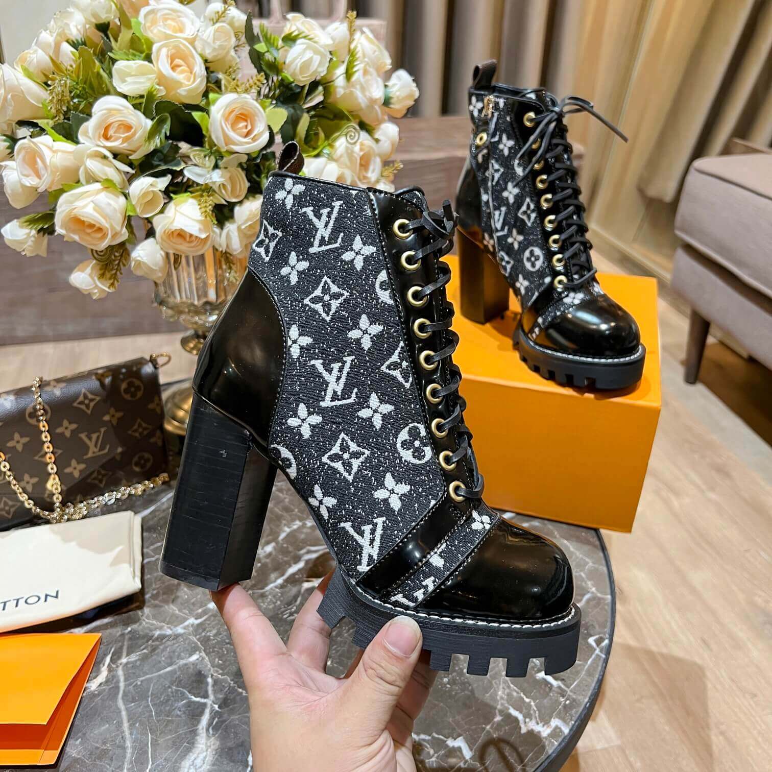 a pair of Louis Vuitton Star Trail Ankle Boots (Black Monogramon a marble table