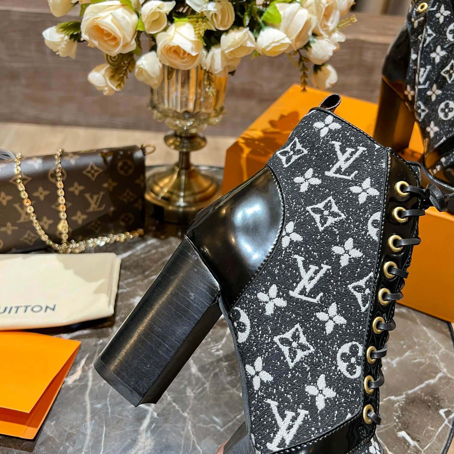 a pair of Louis Vuitton Star Trail Ankle Boots (Black Monogramon a marble table