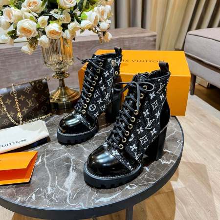 a pair of Louis Vuitton Star Trail Ankle Boots (Black Monogramon a marble table