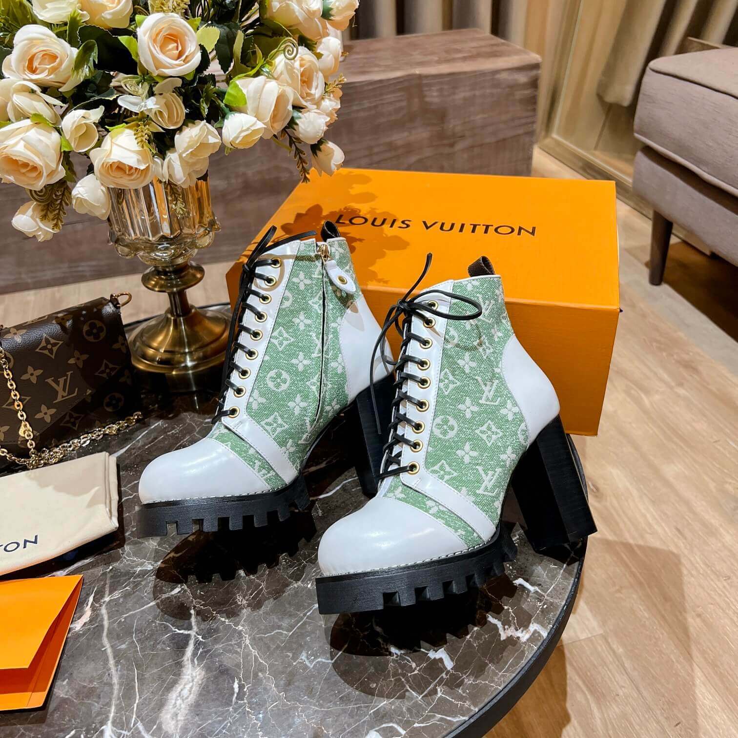 a pair of Louis Vuitton Star Trail Ankle Boots (Green Monogram & White Leather) on a table