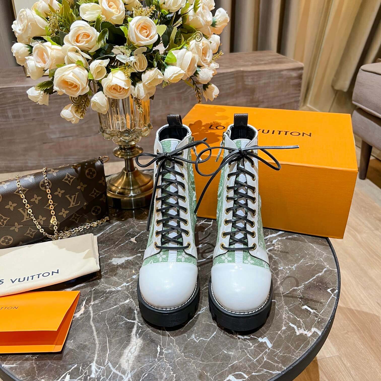 a pair of Louis Vuitton Star Trail Ankle Boots (Green Monogram & White Leather) on a table