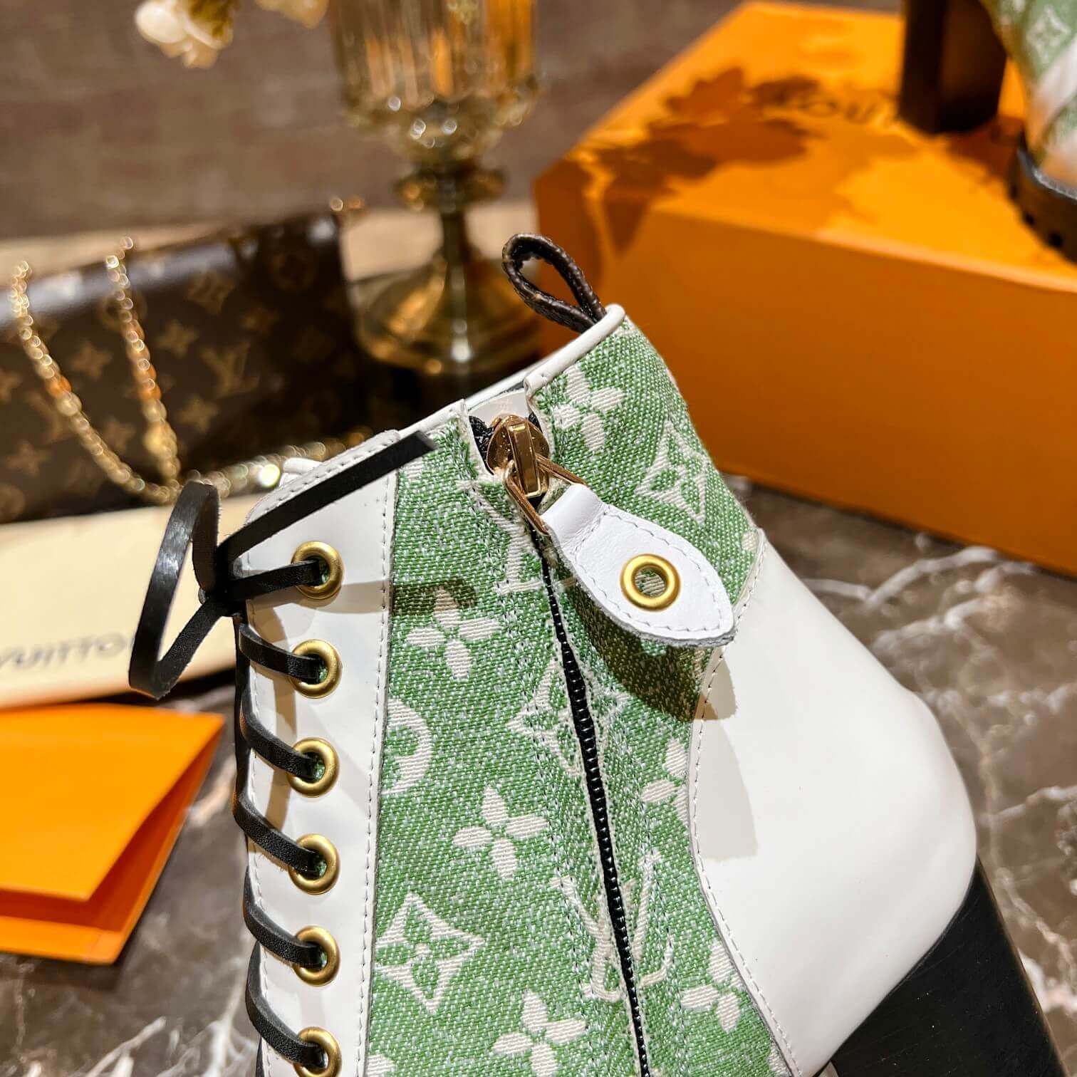 a pair of Louis Vuitton Star Trail Ankle Boots (Green Monogram & White Leather) on a table