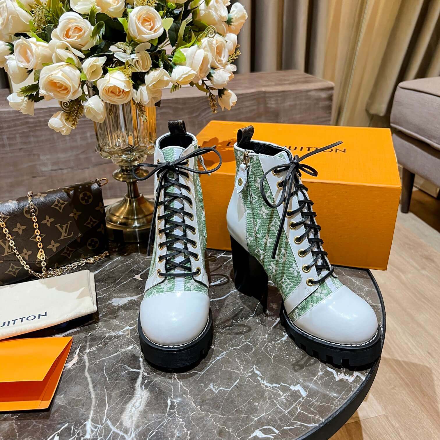 a pair of Louis Vuitton Star Trail Ankle Boots (Green Monogram & White Leather) on a table