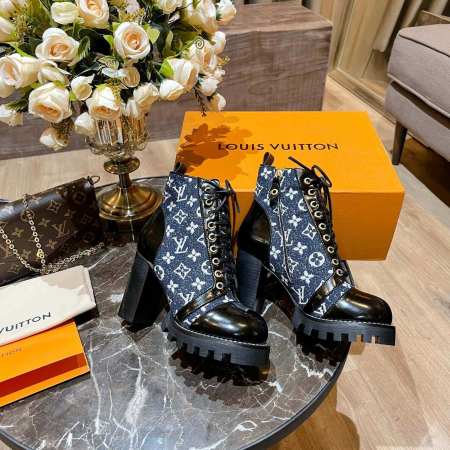 a pair of Louis Vuitton Star Trail Ankle Boots in Blue Monogram Denim and Black Patent Leather on a table