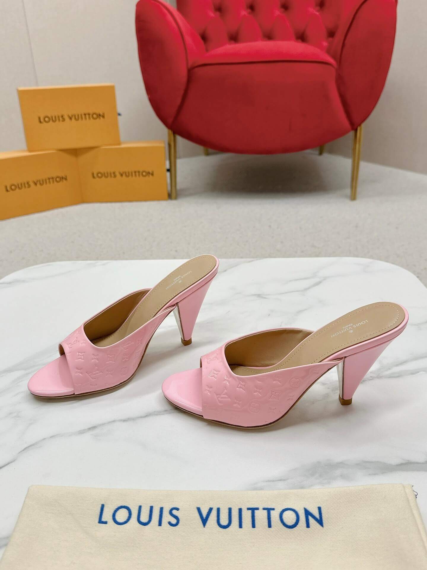 a pair of Louis Vuitton Super Mule – Pink Patent Monogram on a marble surface