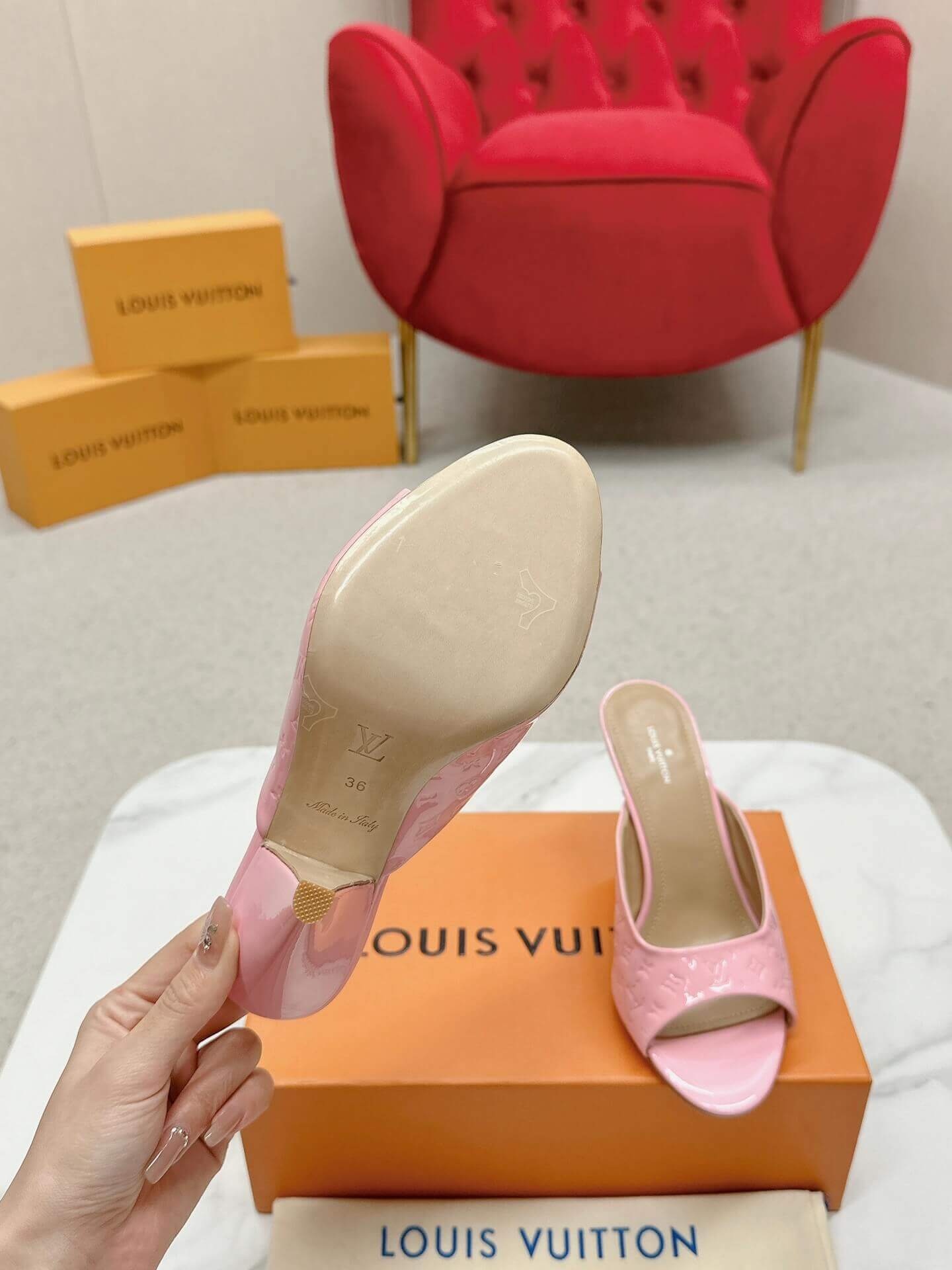 a pair of Louis Vuitton Super Mule – Pink Patent Monogram on a marble surface