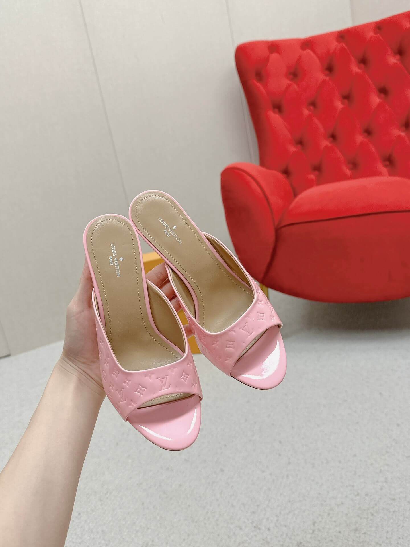 a pair of Louis Vuitton Super Mule – Pink Patent Monogram on a marble surface