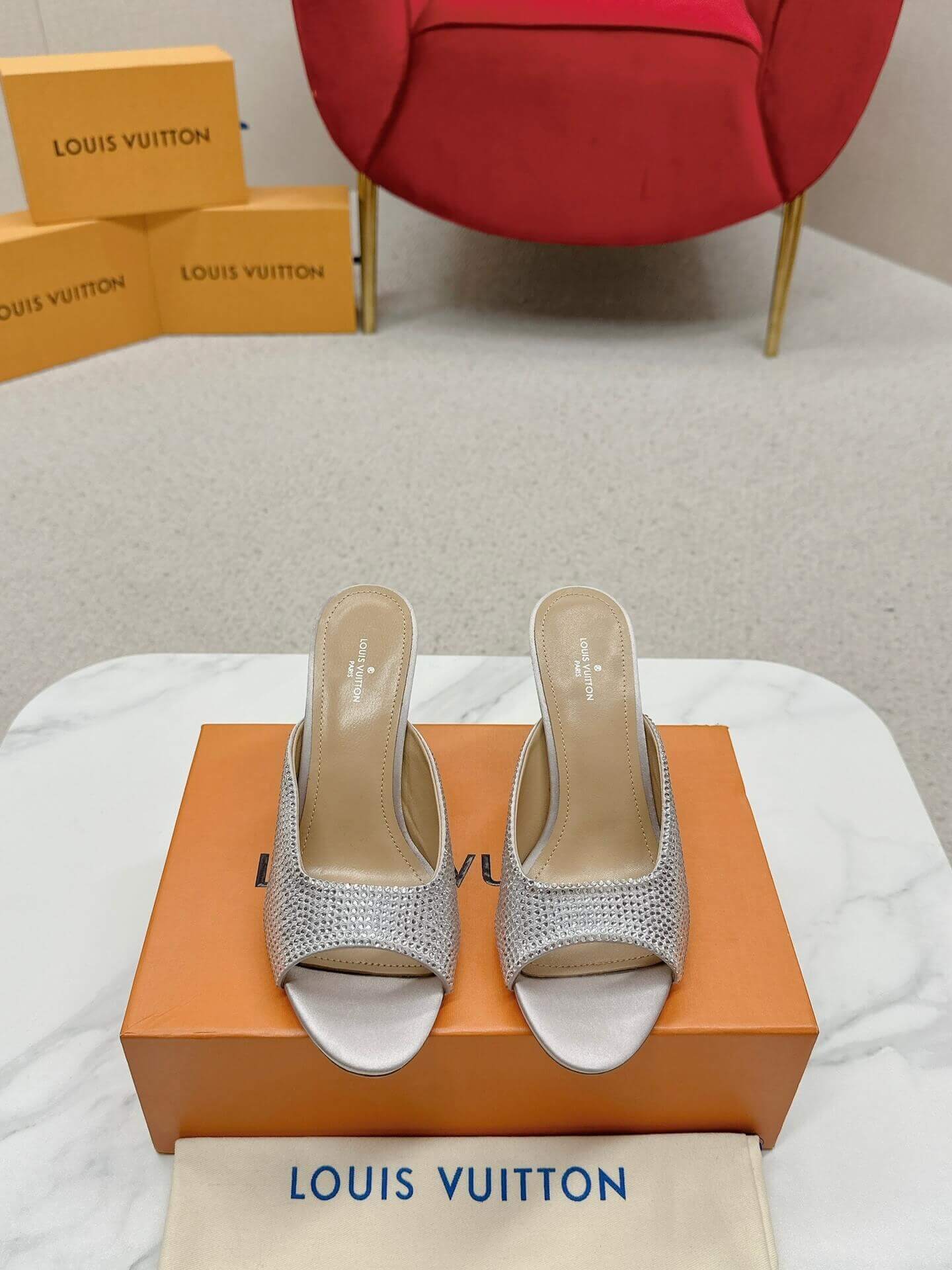 a pair of Louis Vuitton Super Mule – Silver Crystal Elegance on a box