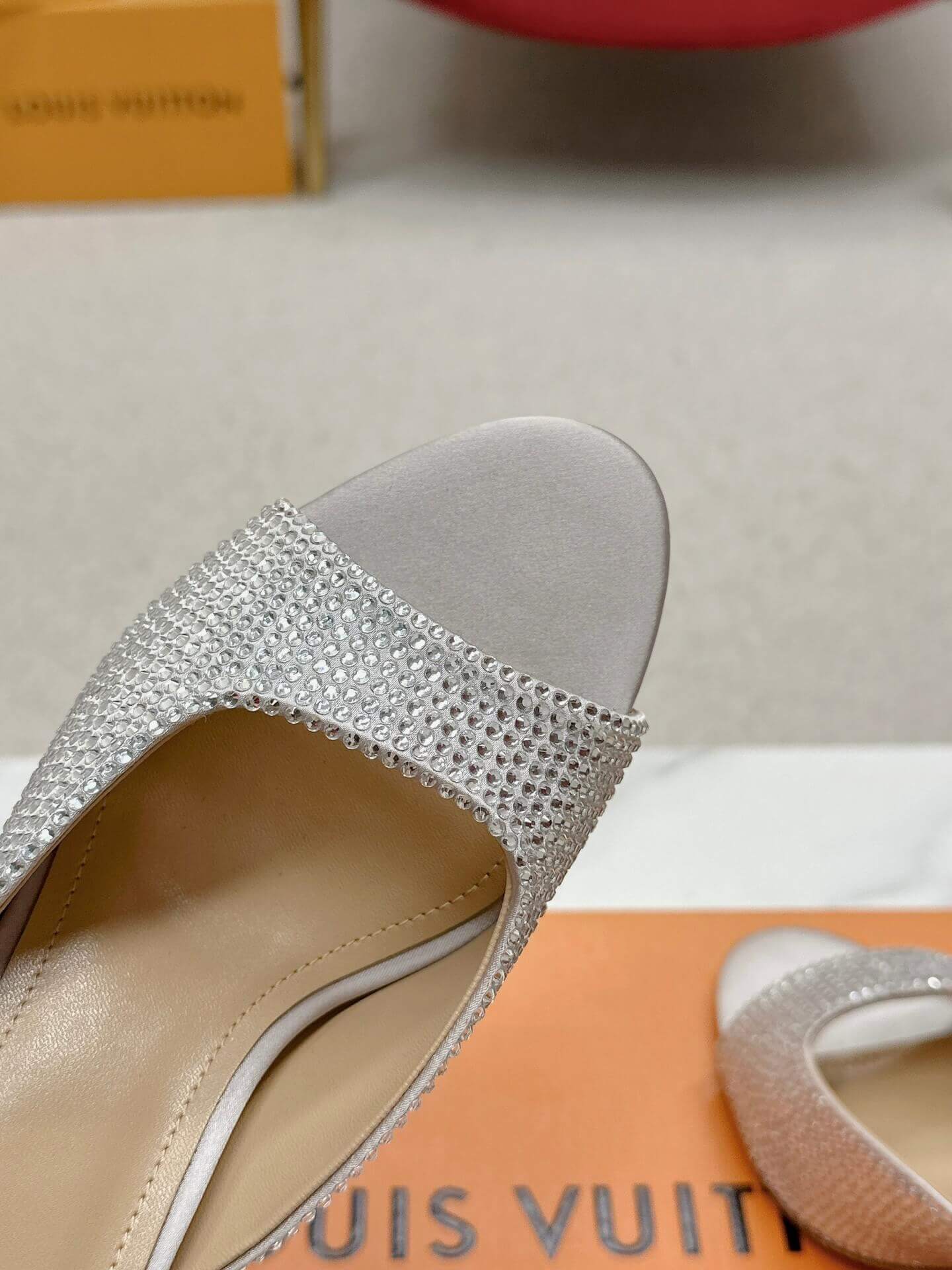 a pair of Louis Vuitton Super Mule – Silver Crystal Elegance on a box