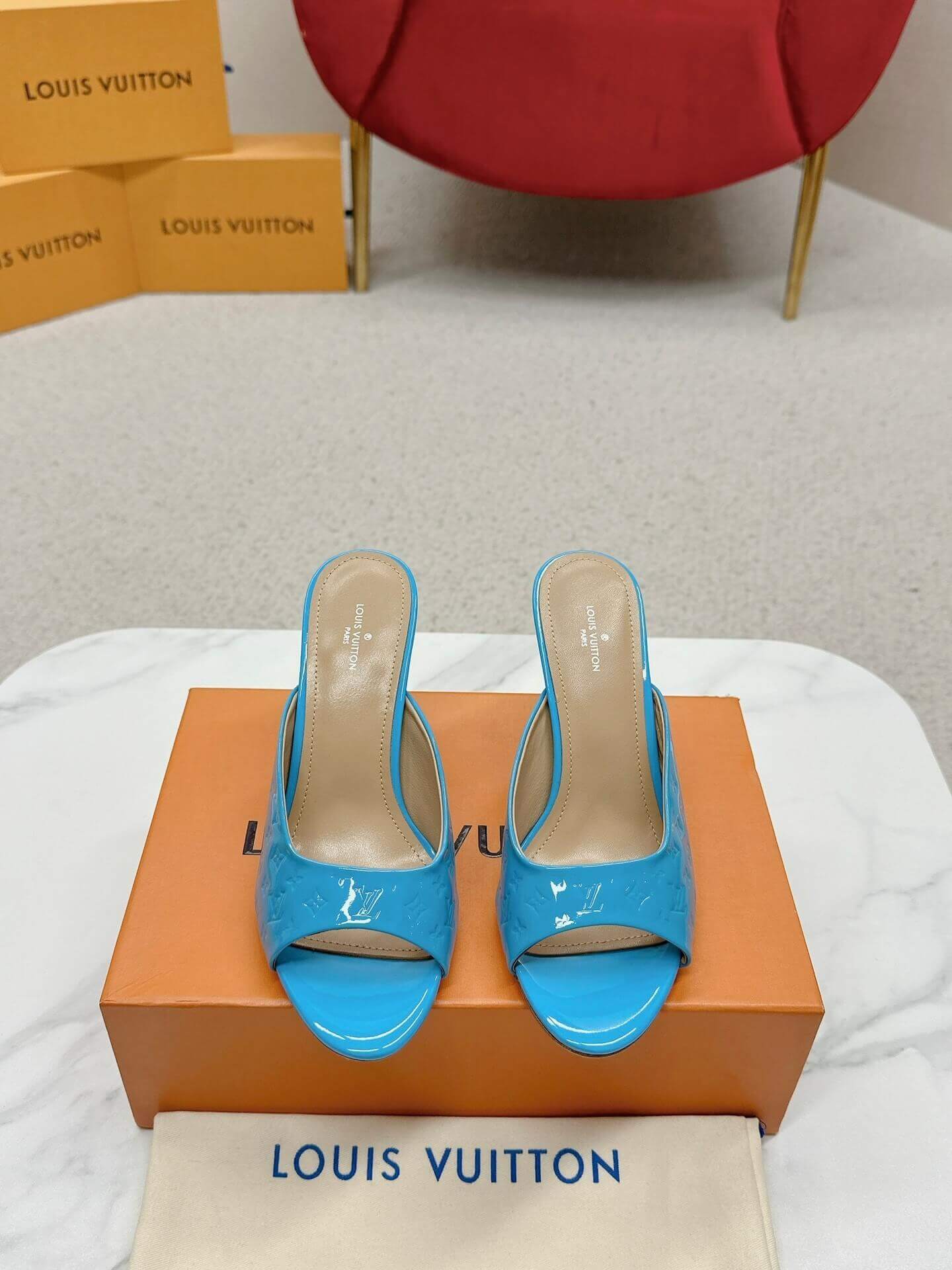 a pair of Louis Vuitton Super Mule in Sky‑Blue Patent on a marble surface