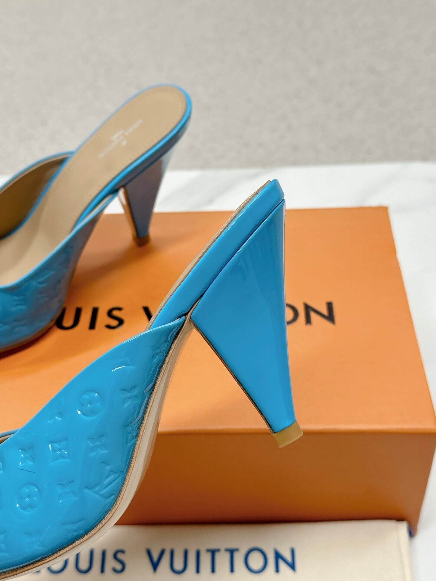 a pair of Louis Vuitton Super Mule in Sky‑Blue Patent on a marble surface