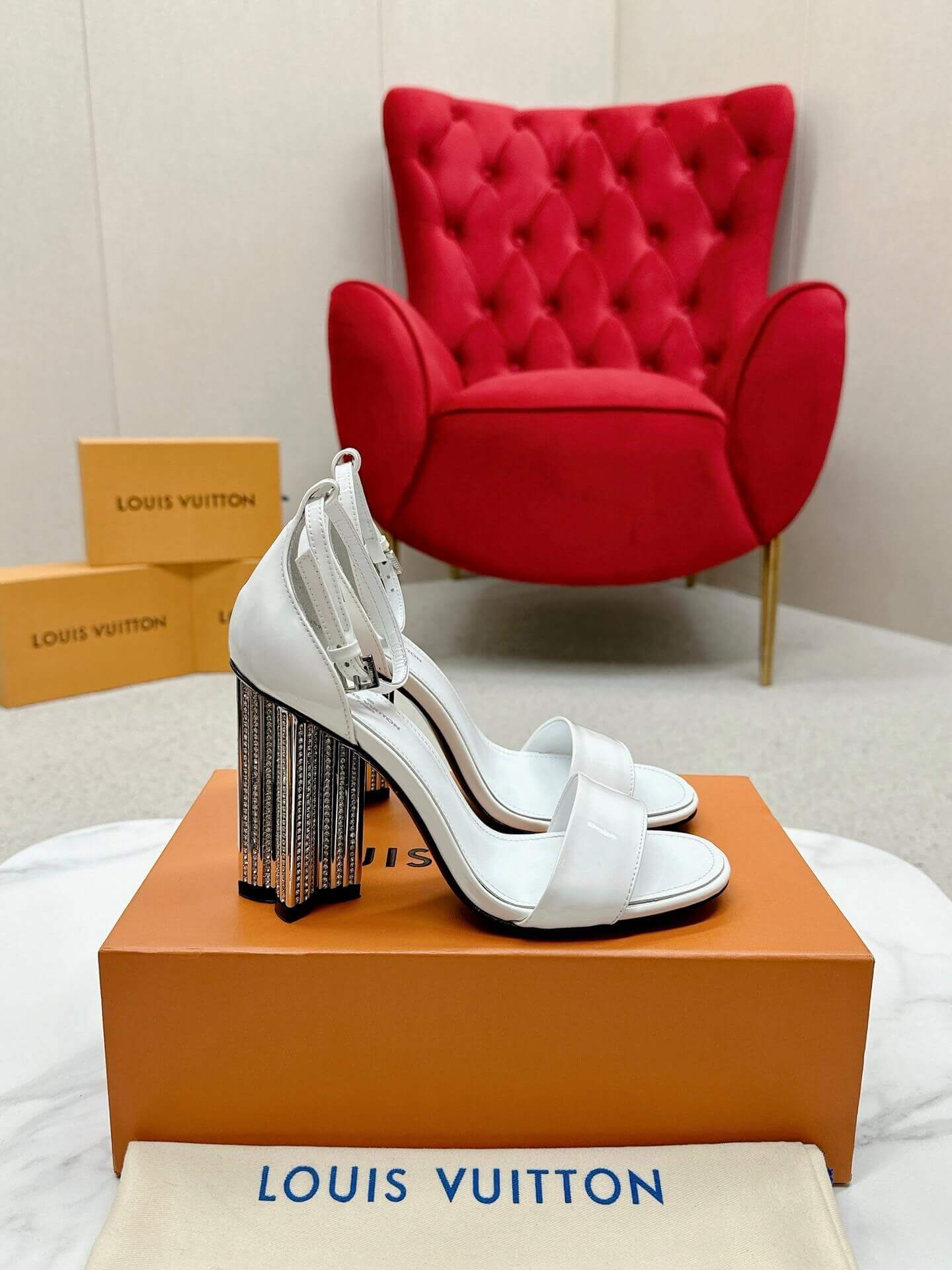 a pair of Louis Vuitton White Patent Leather Silhouette Sandals with Monogram Heel on a box