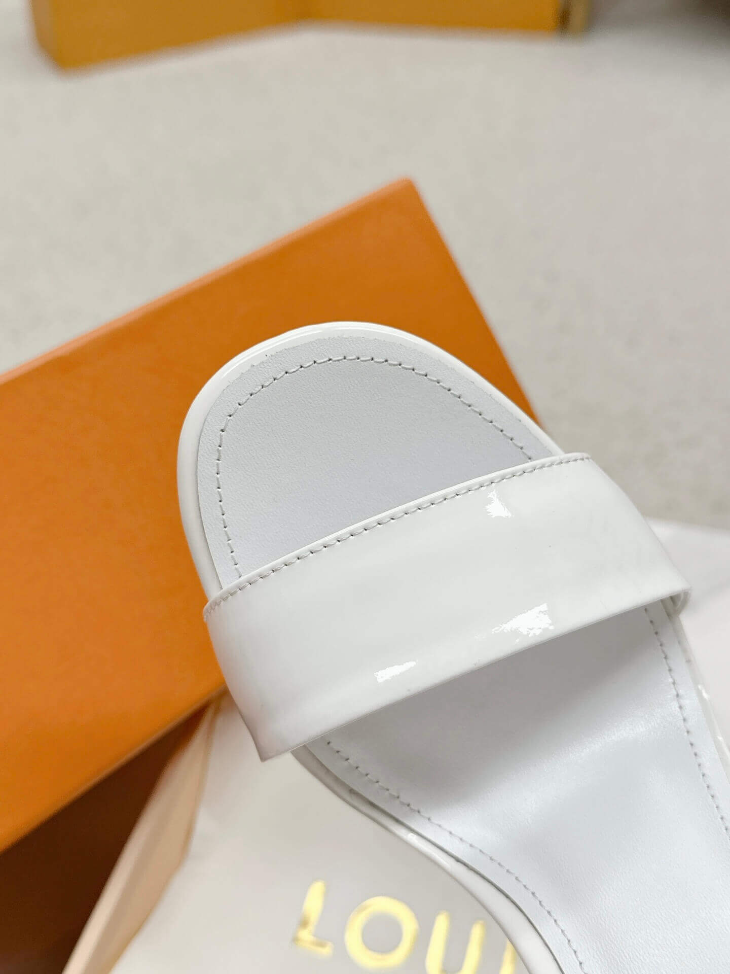 a pair of Louis Vuitton White Patent Leather Silhouette Sandals with Monogram Heel on a box