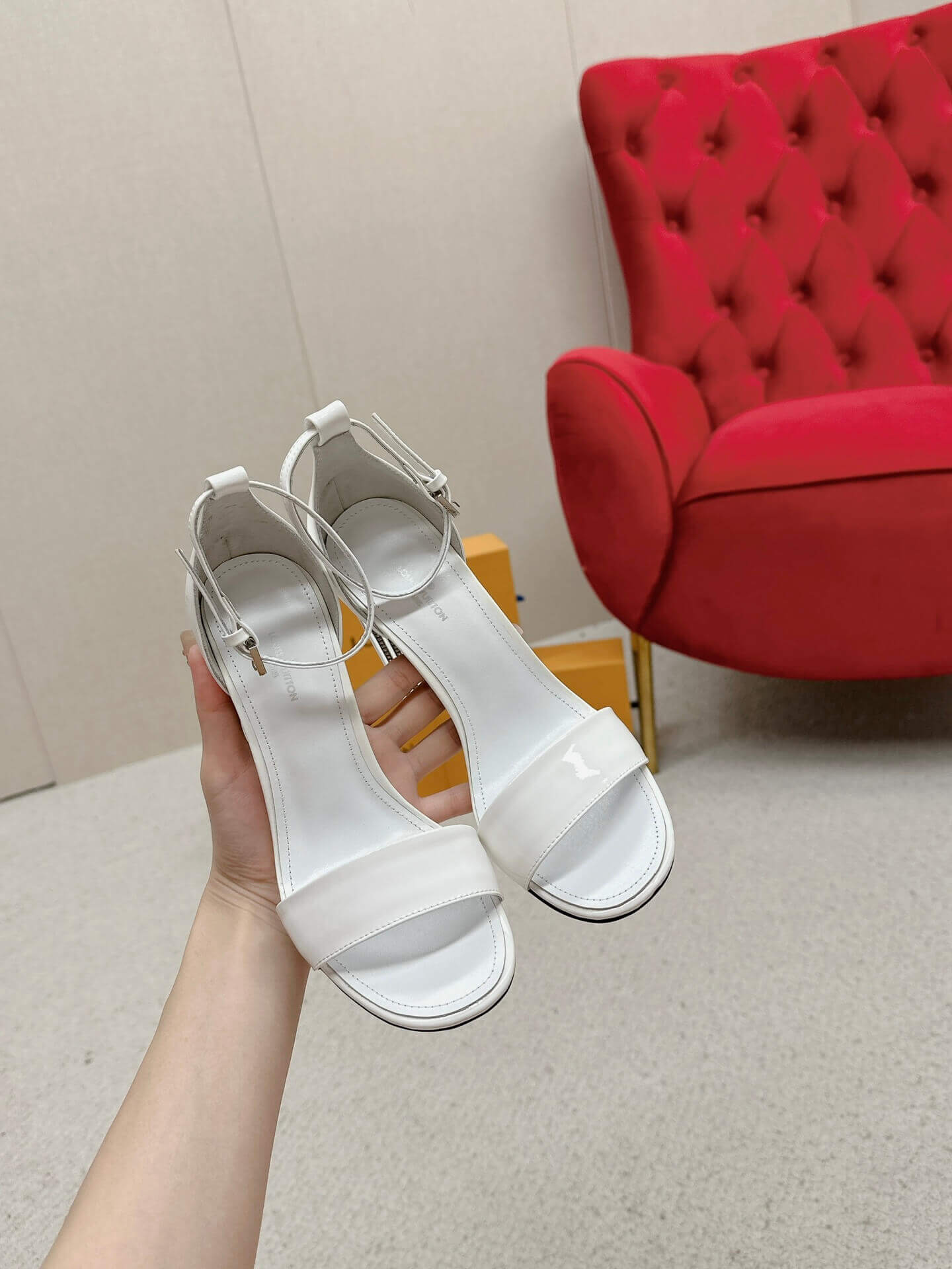 a pair of Louis Vuitton White Patent Leather Silhouette Sandals with Monogram Heel on a box