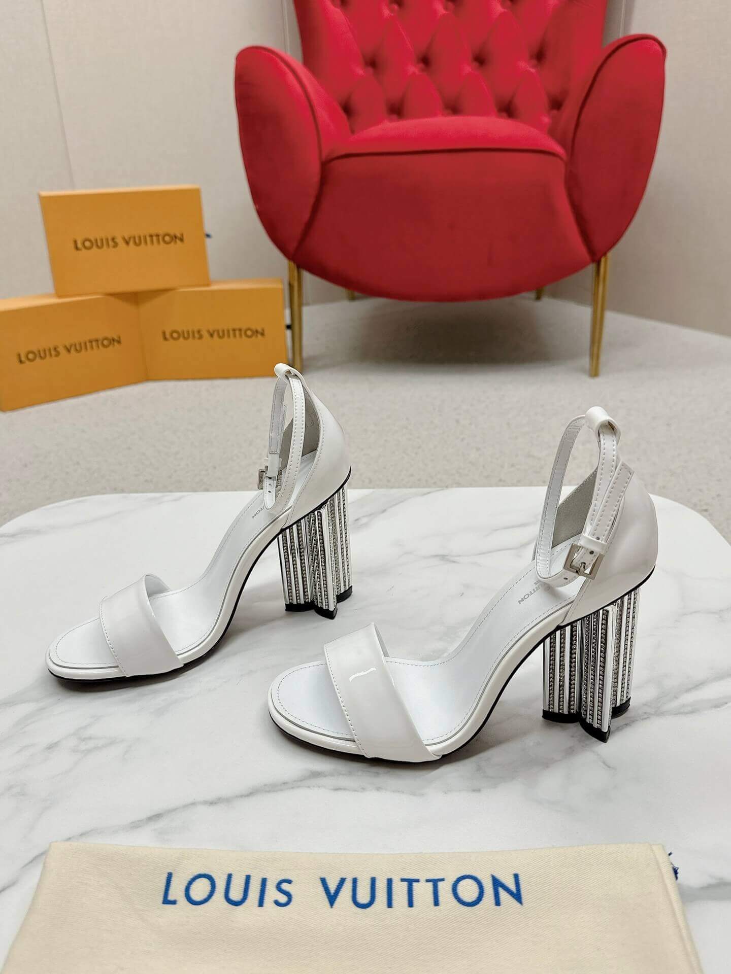 a pair of Louis Vuitton White Patent Leather Silhouette Sandals with Monogram Heel on a box