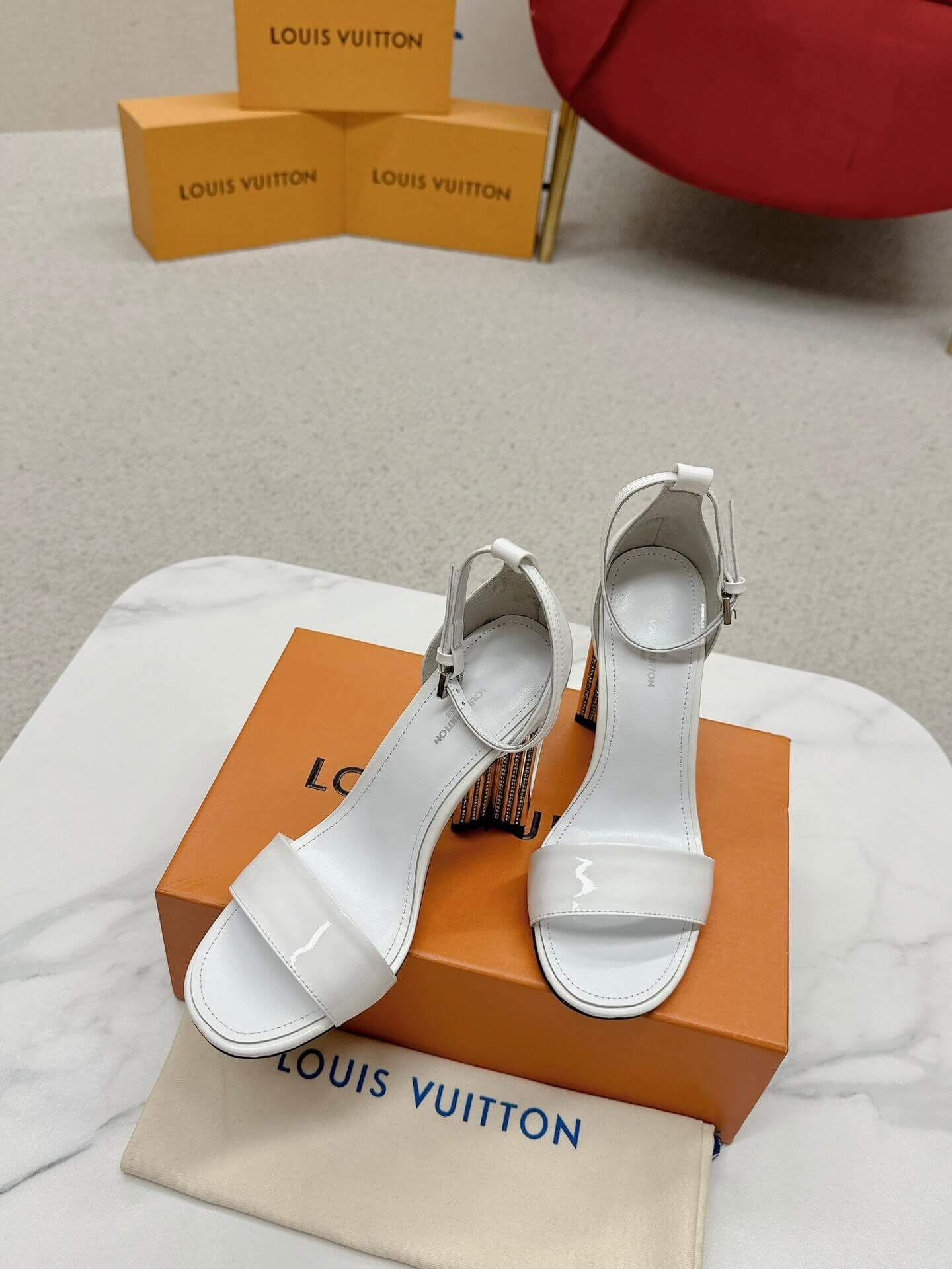 a pair of Louis Vuitton White Patent Leather Silhouette Sandals with Monogram Heel on a box